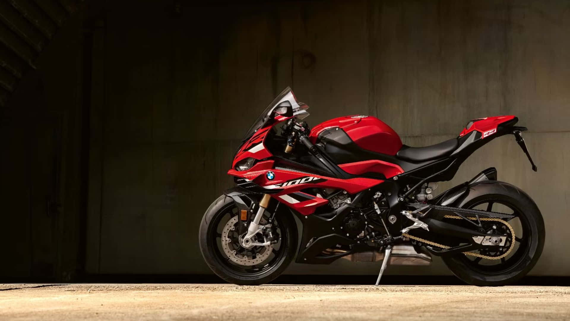  壁紙 — 一台搶眼的紅黑色BMW S1000RR摩托車，在燈光昏暗的混凝土車庫中，以戲劇性的燈光呈現。