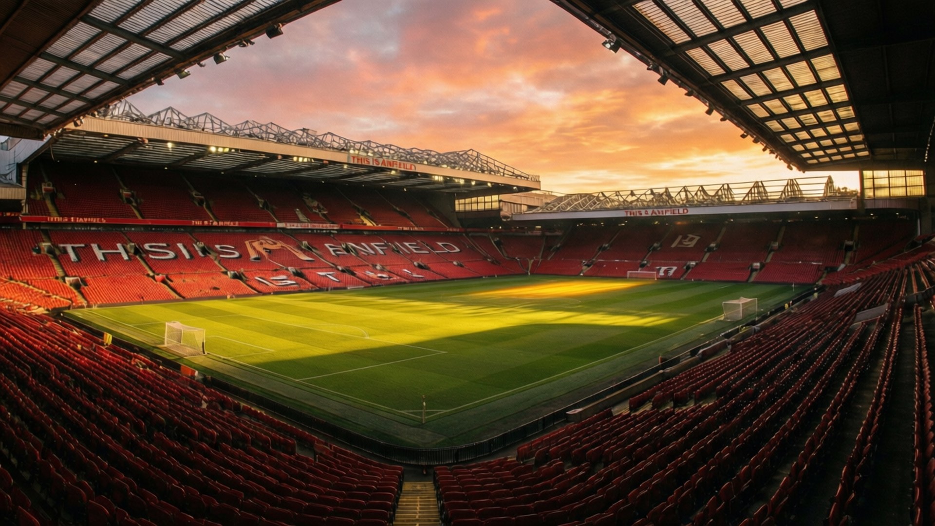 Anfield 桌布 壁紙 — 夕陽下奧脫福球場的廣闊景觀，金色光芒照亮綠色草坪和紅色座位。