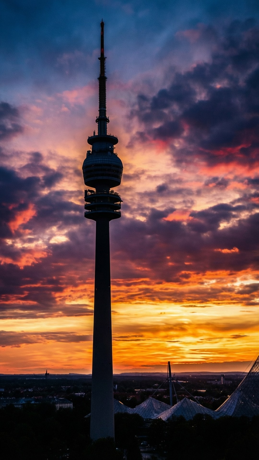 Olympiaturm at Sunset 壁紙 — 一座高塔在戲劇性的日落天空下呈現剪影，天空被塗上火焰般的橙色、粉紅色和深紫色雲彩。