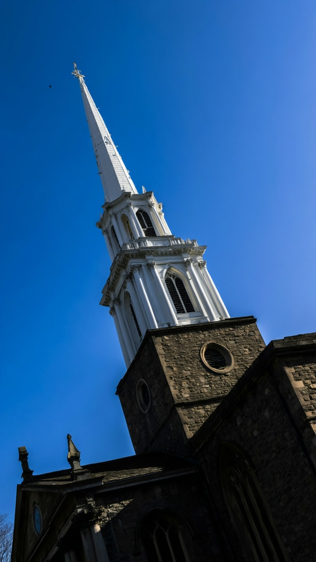Christ Church Spire 壁紙 — 一座高大的白色教堂尖塔，帶有尖頂，在清澈的藍天下 sharply 升起。