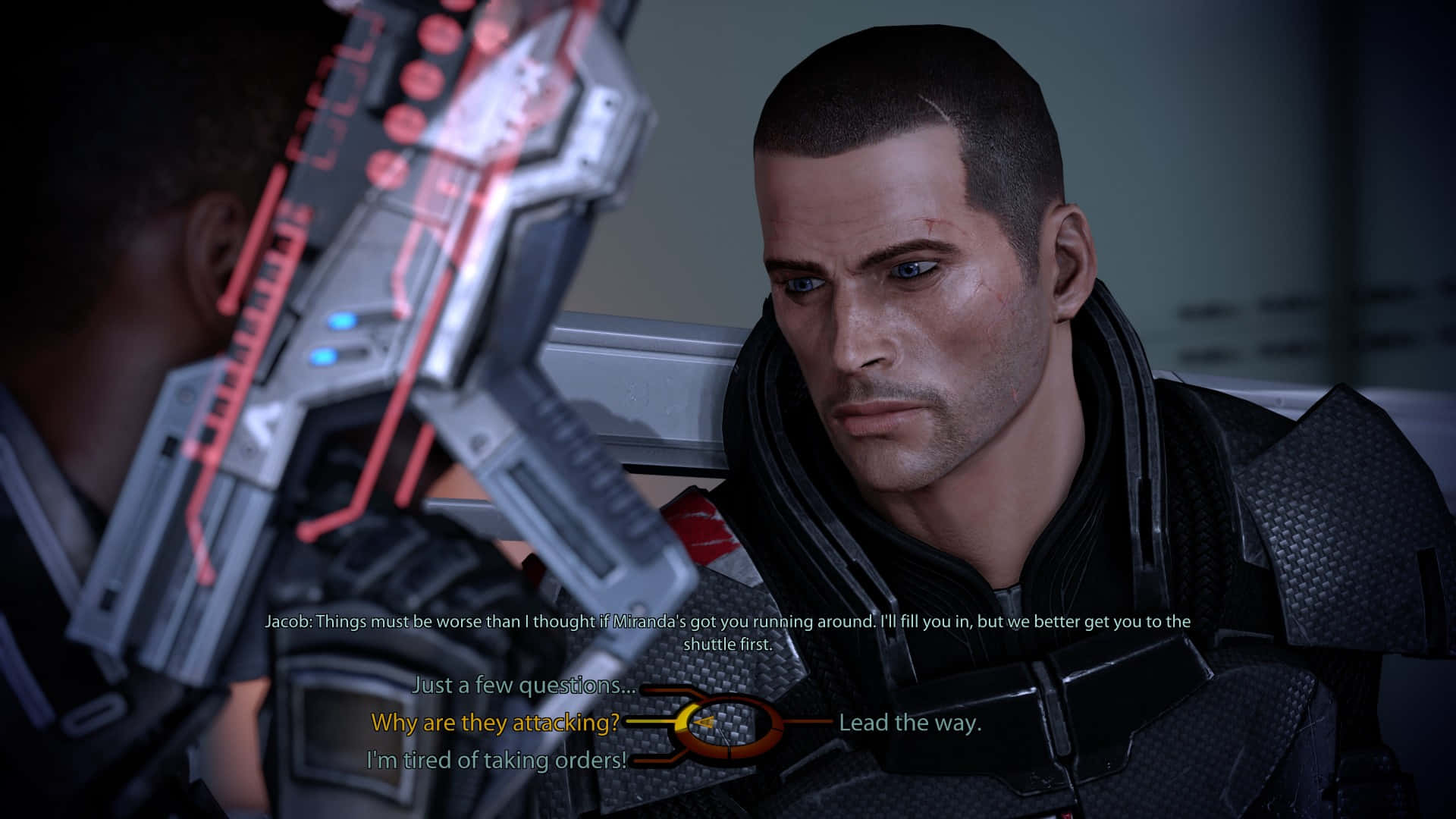 Mass Effect Legendary Edition 桌布 壁紙 — 一個緊張的特寫鏡頭，一名身穿未來裝甲的士兵手持發光的紅色武器，面對另一個角色，背景是昏暗的科幻場景。