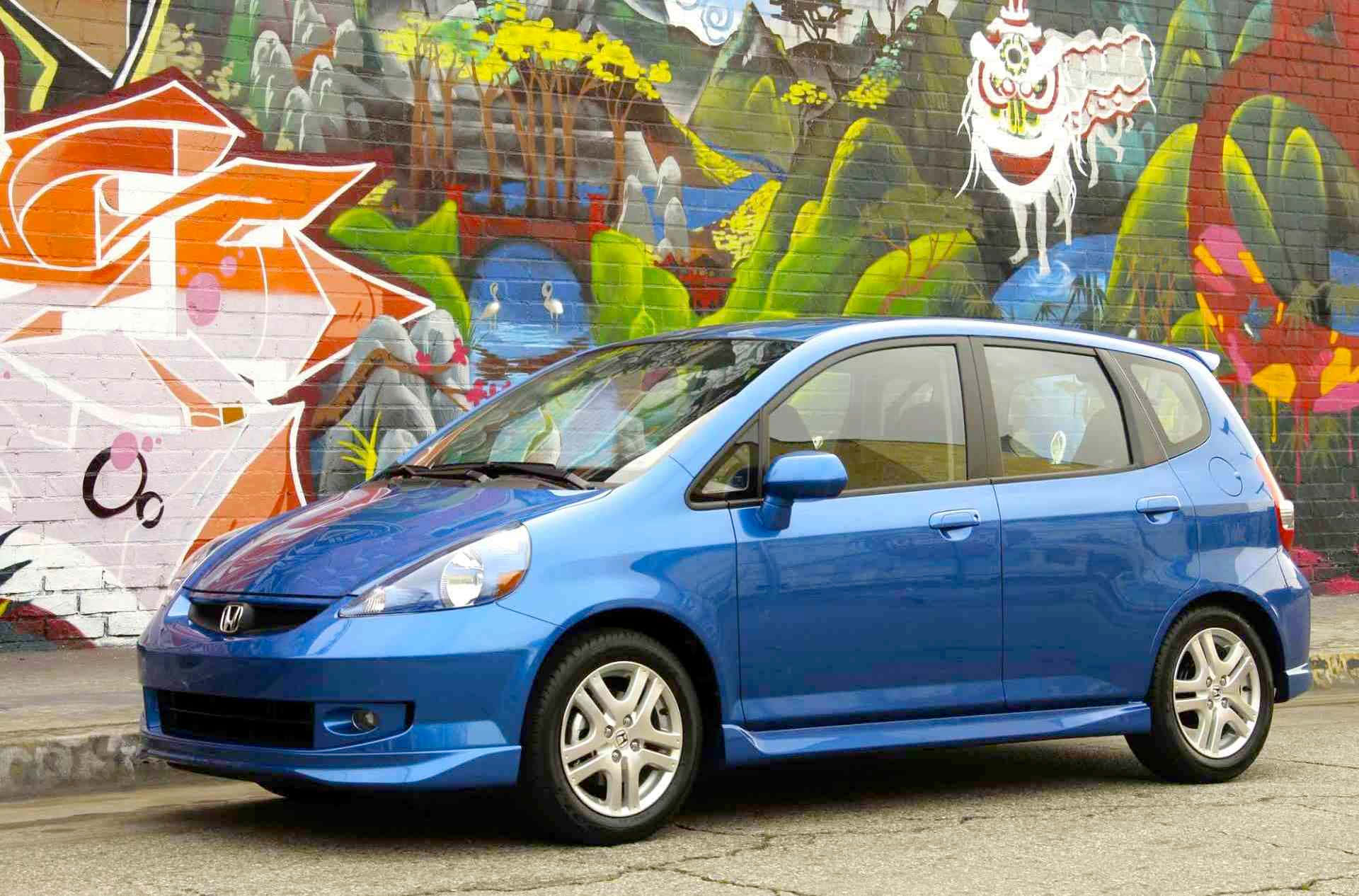 Honda Fit 桌布 壁紙 — 一輛充滿活力的藍色本田Fit停在一幅色彩繽紛、佈滿塗鴉的牆前，牆上有卡通風格的山脈和動物壁畫。