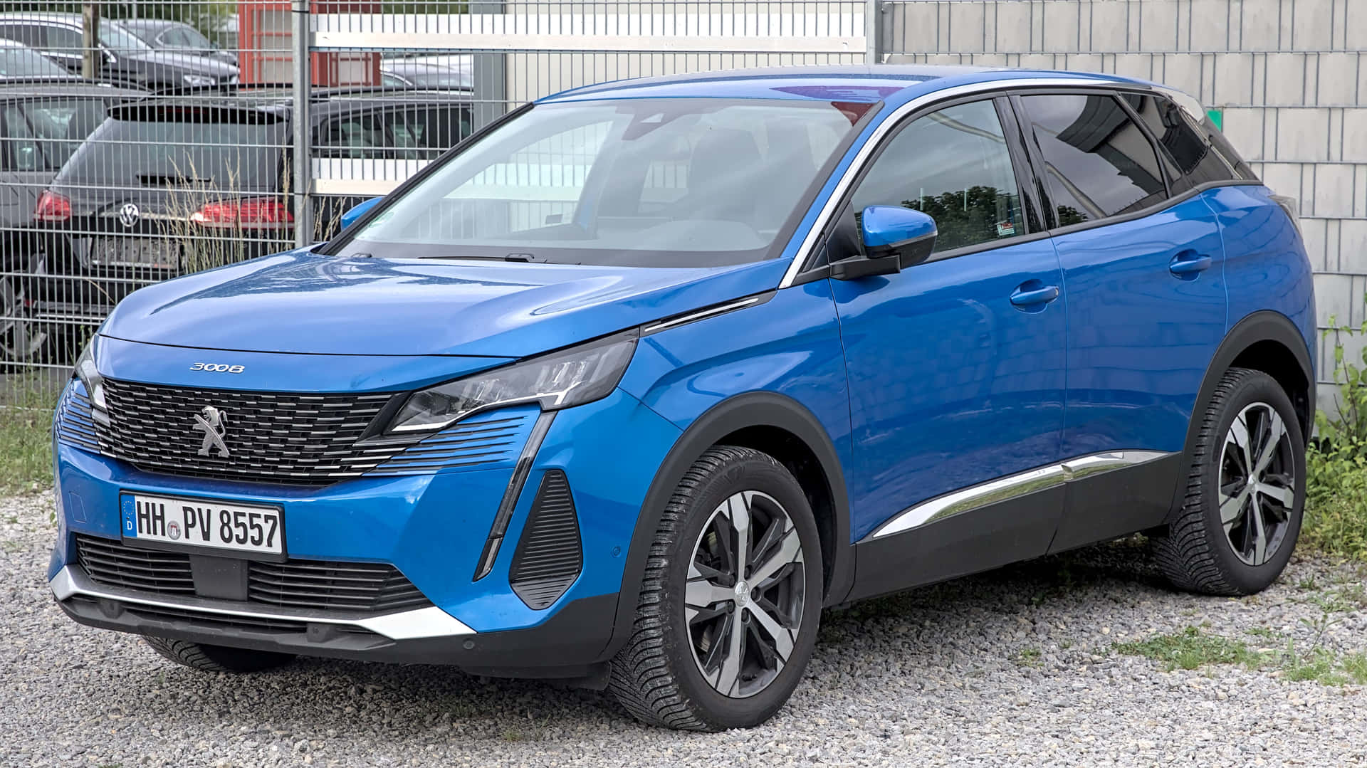  壁紙 — 一輛鮮藍色的Peugeot 3008 SUV停放在碎石上，背景有金屬圍欄和磚牆。