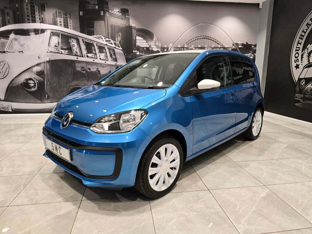 壁紙 — 一輛充滿活力的藍色Volkswagen up!在時尚的展示間中展示，地板鋪有瓷磚，牆上掛有復古VW壁畫。