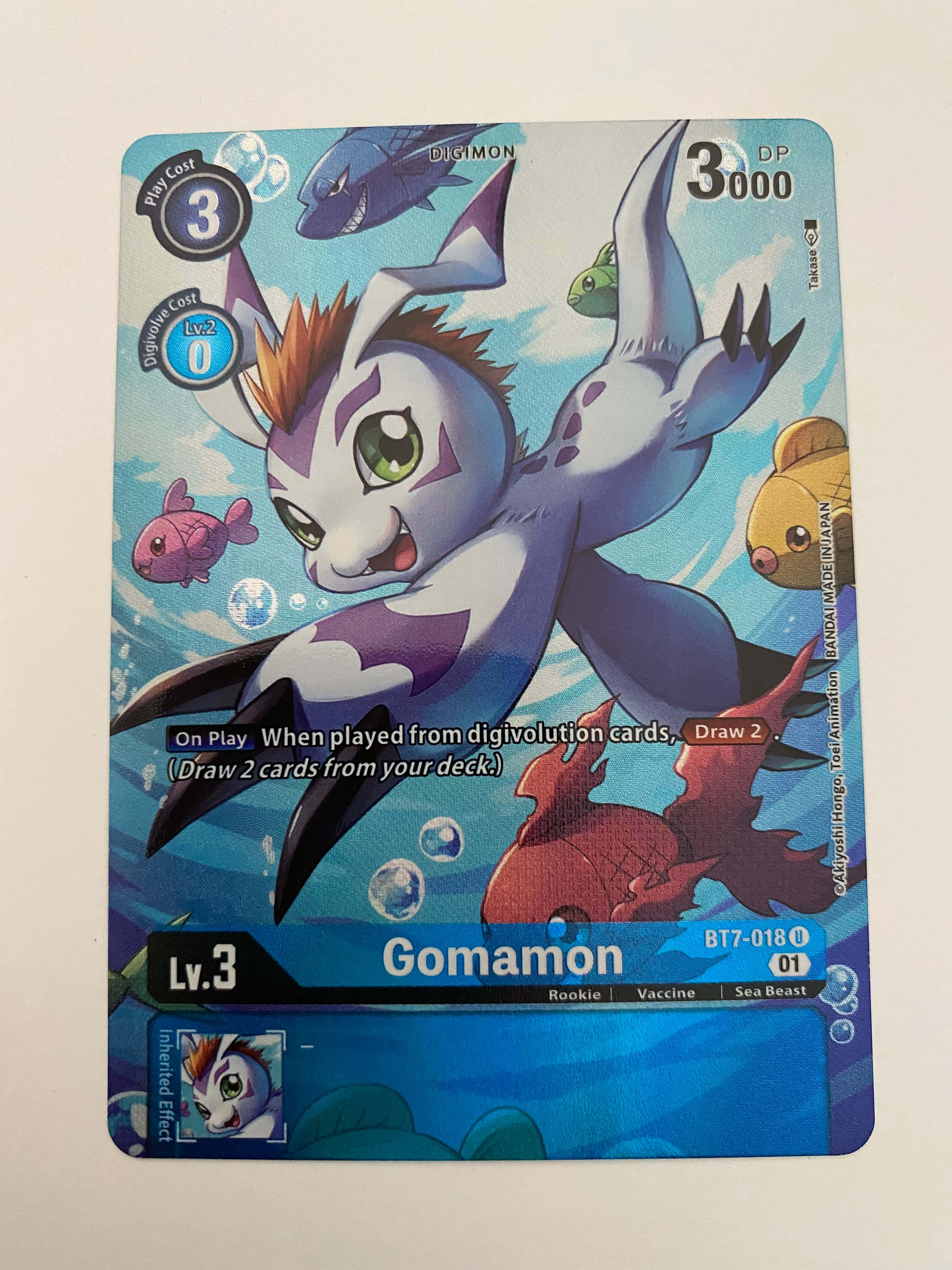 Digimon Gomamon 桌布 壁紙 — 一張充滿活力的數碼寶貝集換式卡牌，描繪哥瑪獸在水下與色彩繽紛的魚和氣泡一起游泳。