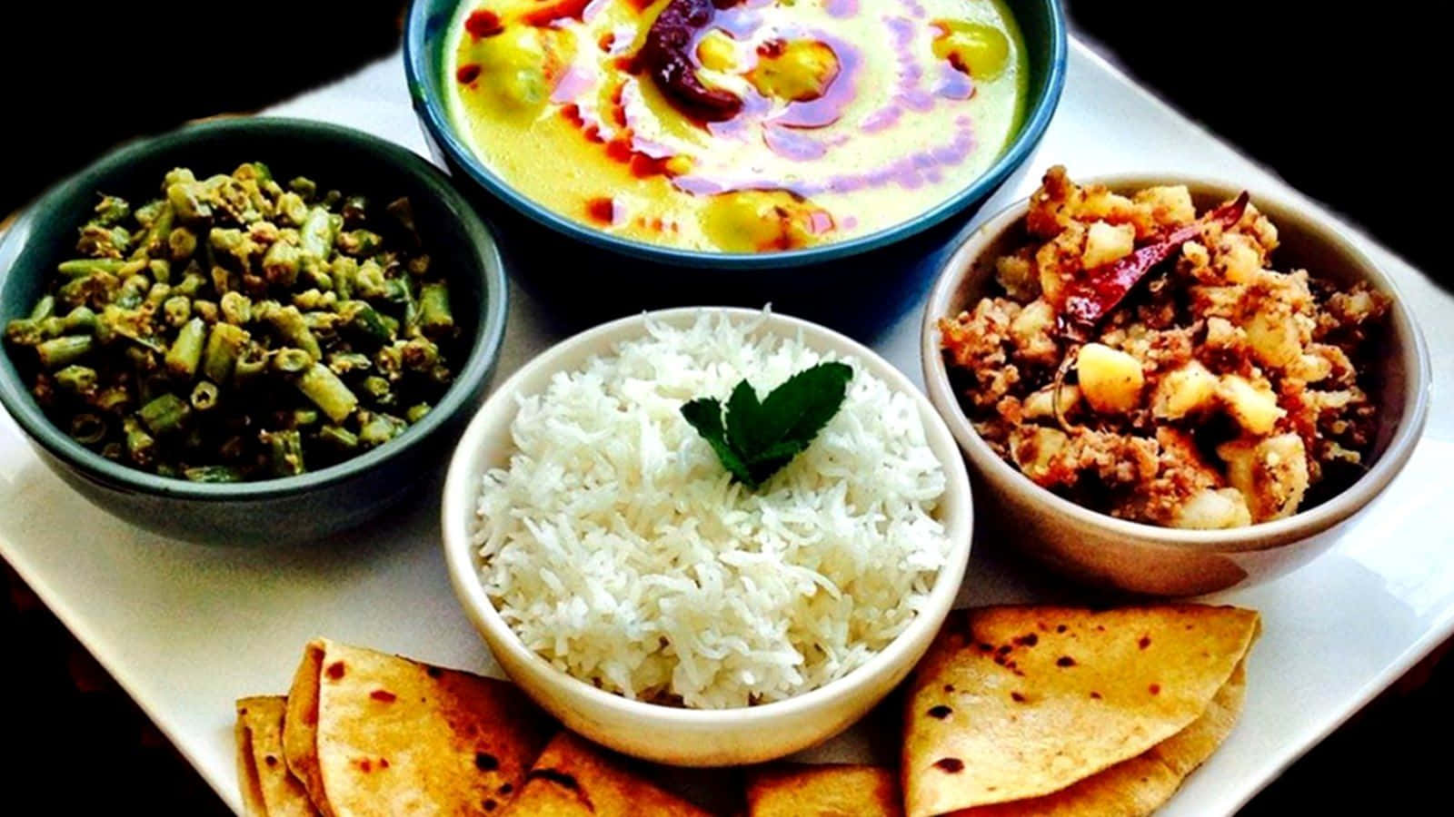 Thali 桌布 壁紙 — 充滿活力的印度餐，包括米飯、豆泥、酸辣醬和印度烤餅，擺放在白色托盤上，配以色彩繽紛的醬汁和裝飾。