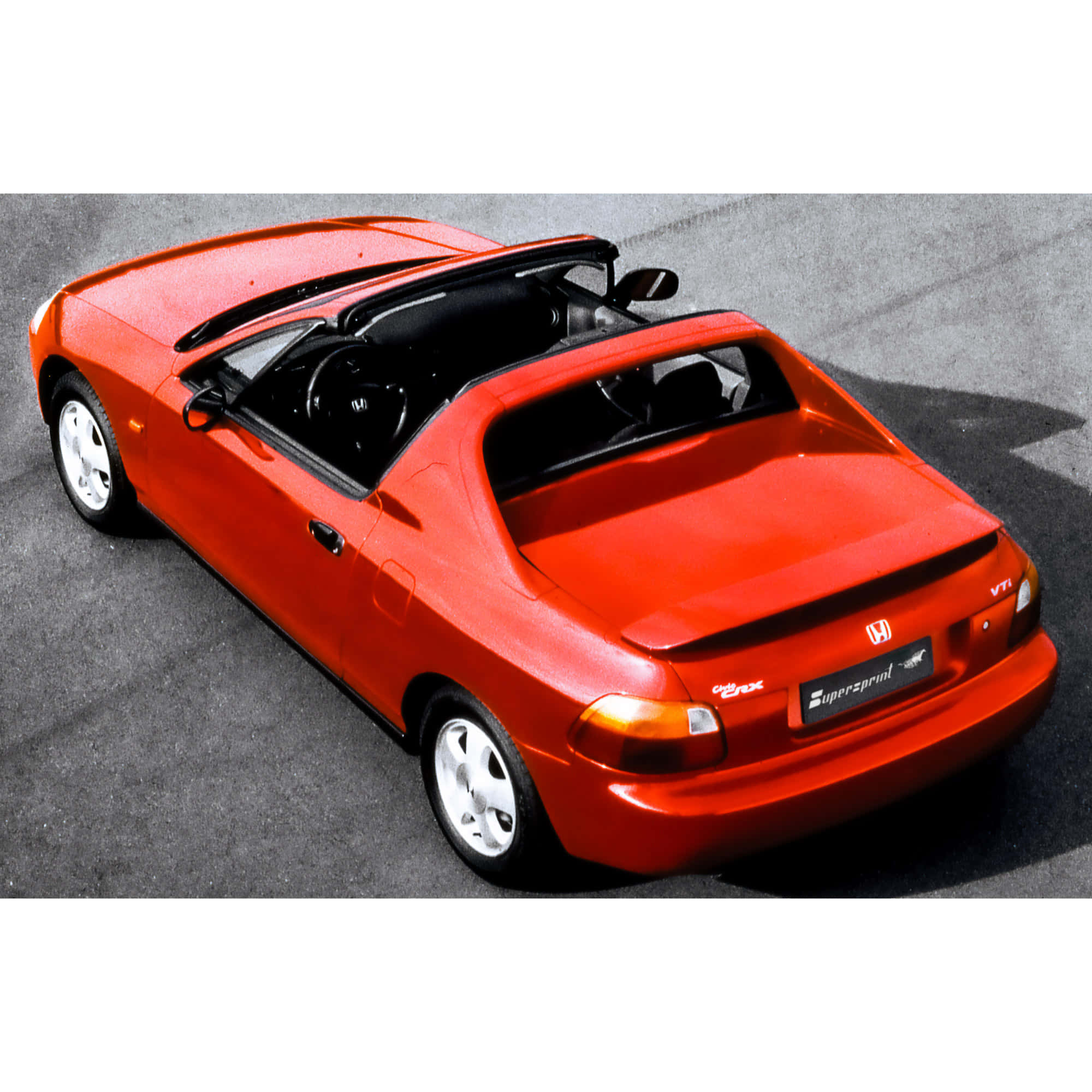 Honda Civic Del Sol 桌布 壁紙 — 一輛鮮紅色的本田S2000敞篷跑車在明亮的日光下停放在灰色瀝青路上。