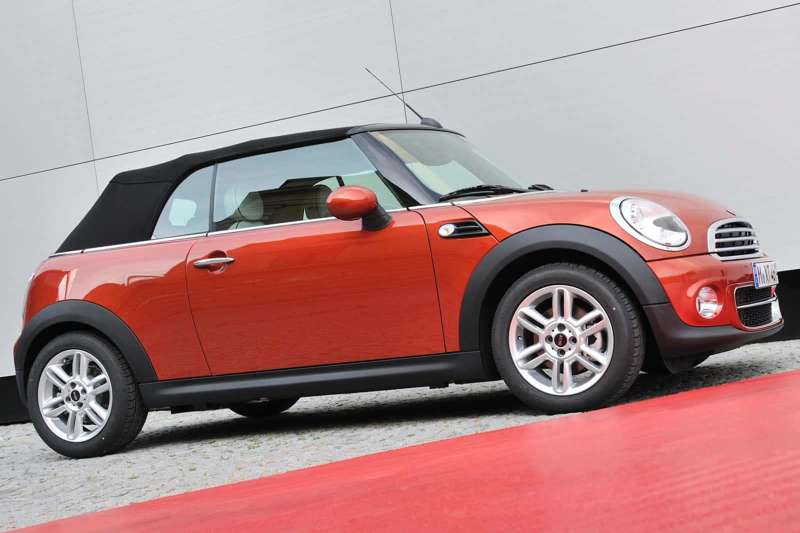 Mini Cooper Convertible 桌布 壁紙 — 一輛鮮紅色的MINI Cooper敞篷車停在紅色地毯上，背景是簡約的灰色牆壁。