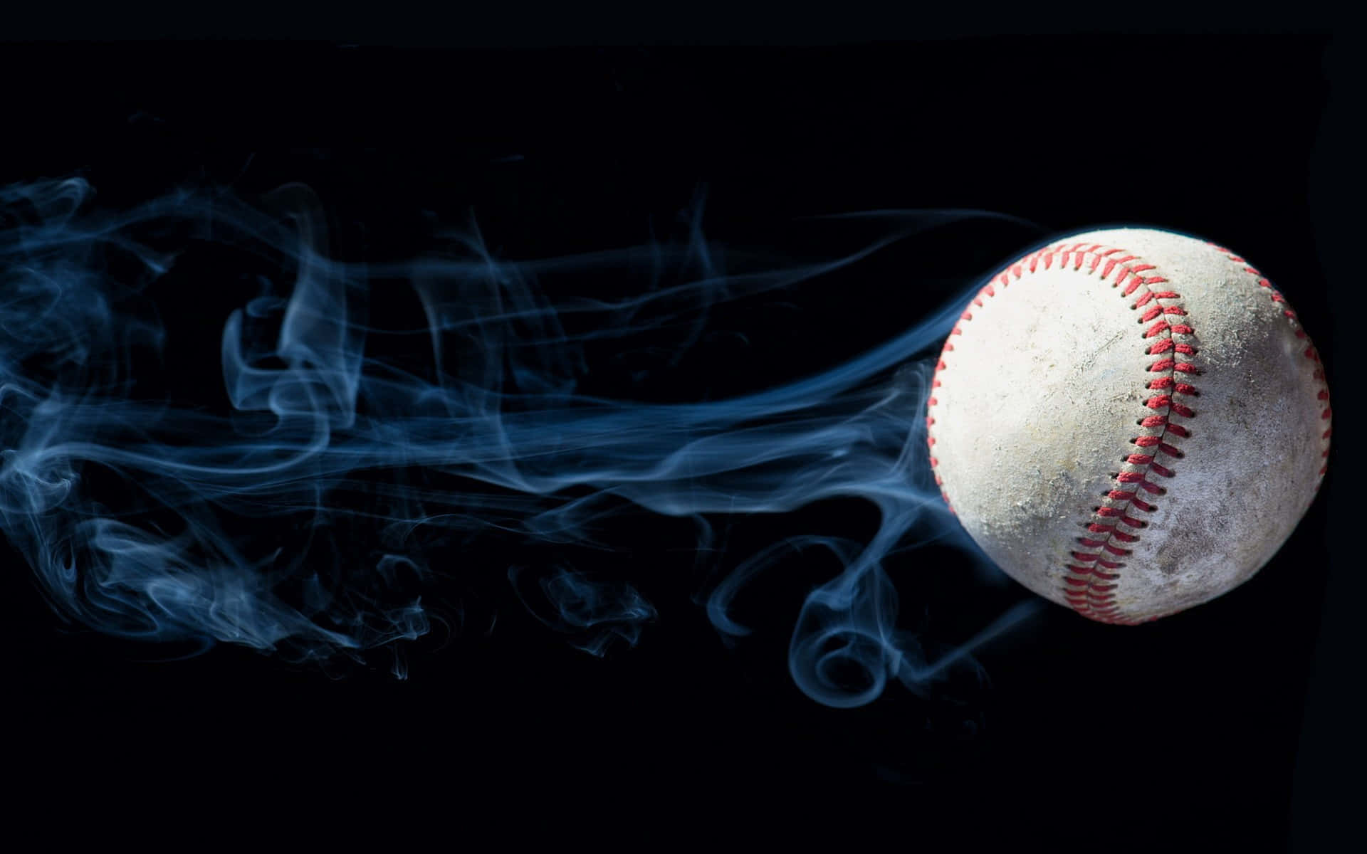 一顆帶有紅色縫線的骯髒棒球在黑色背景上散發出藍色煙霧。 — MLB 壁紙