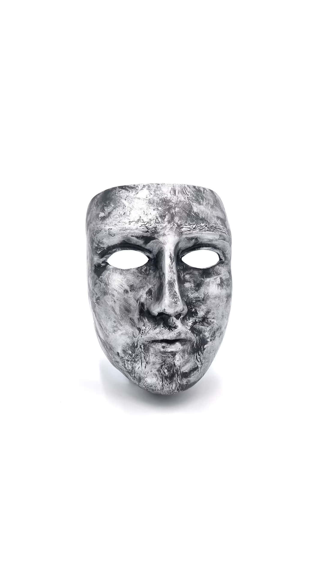  壁紙 — 一個風化的銀色面具，帶有空洞的眼睛和紋理表面，位於純白色背景的中心。