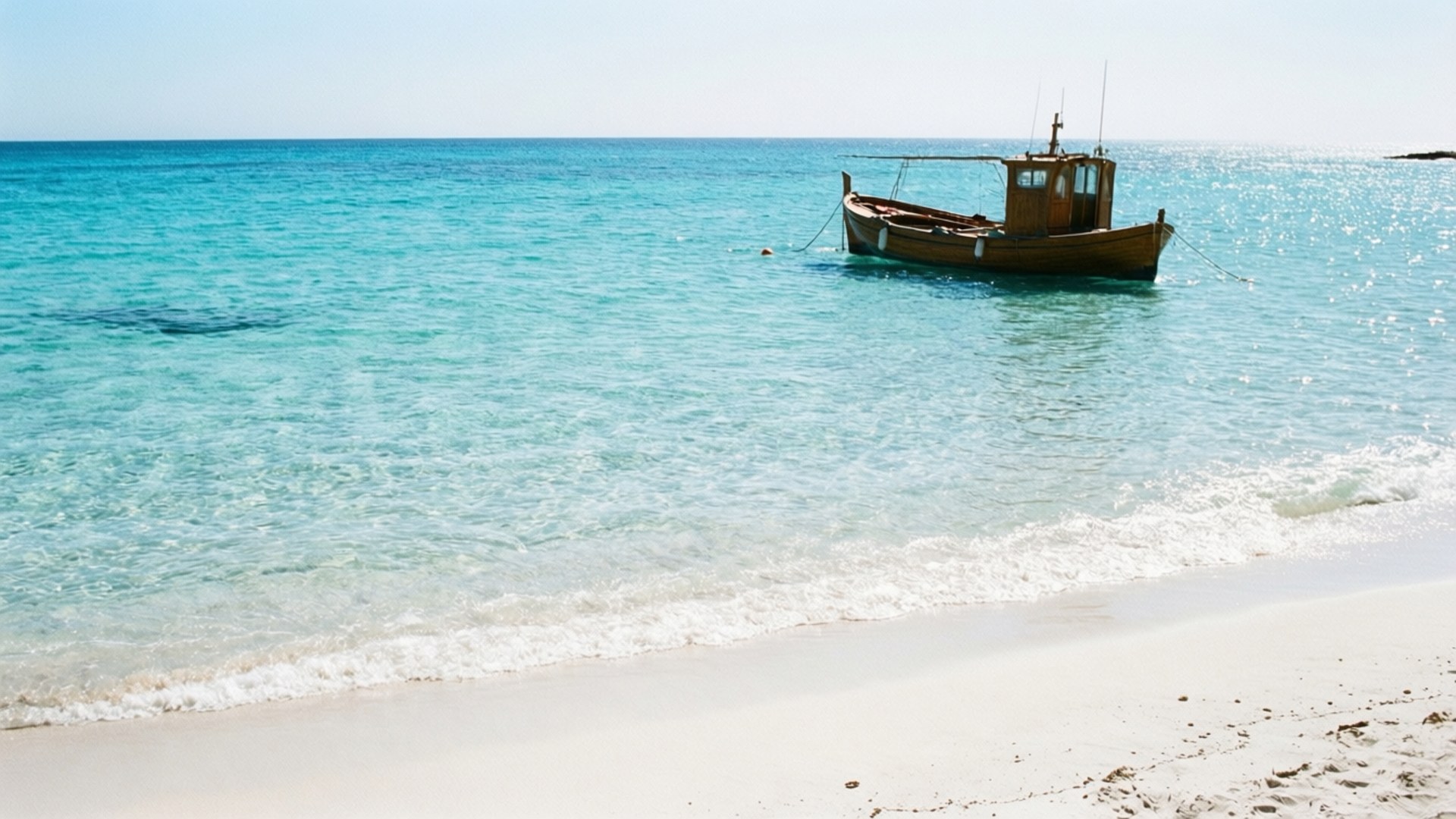 Formentera Paradise Beach 壁紙 — 一艘風化的木製漁船在清澈的碧綠海水上平靜地漂浮，靠近純淨的白色沙灘。