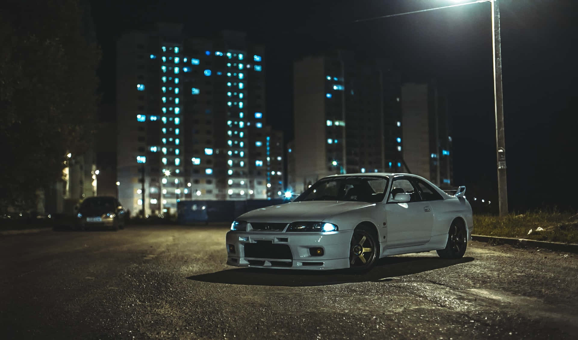 白色跑車停在夜間濕潤的城市街道上，在街燈下。 — 日產Skyline GTR R33壁紙 壁紙