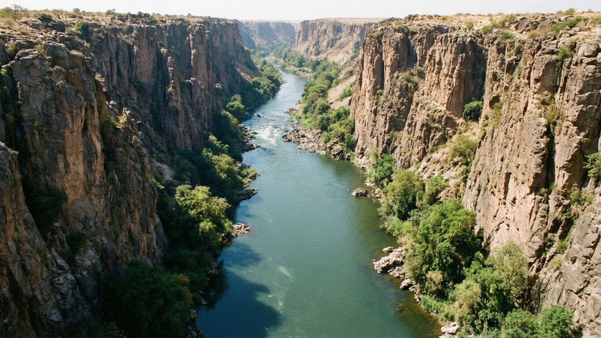 Sabaloka Gorge 壁紙 — 一條蜿蜒的河流流經深邃的峽谷，兩岸有陡峭的岩石懸崖和茂密的綠色植被。