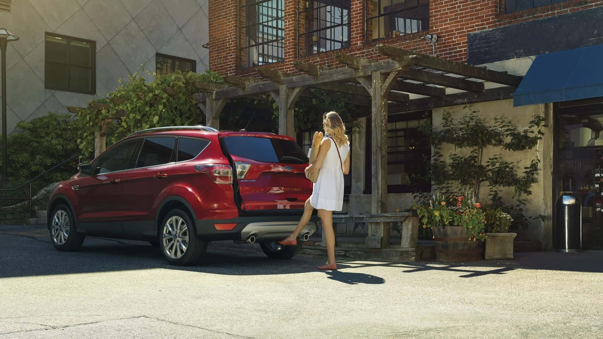 Ford Escape 桌布 壁紙 — 一位身穿白色連衣裙的女性站在一輛紅色SUV旁邊，該車停在一棟帶有木製涼棚和盆栽植物的磚砌建築前。