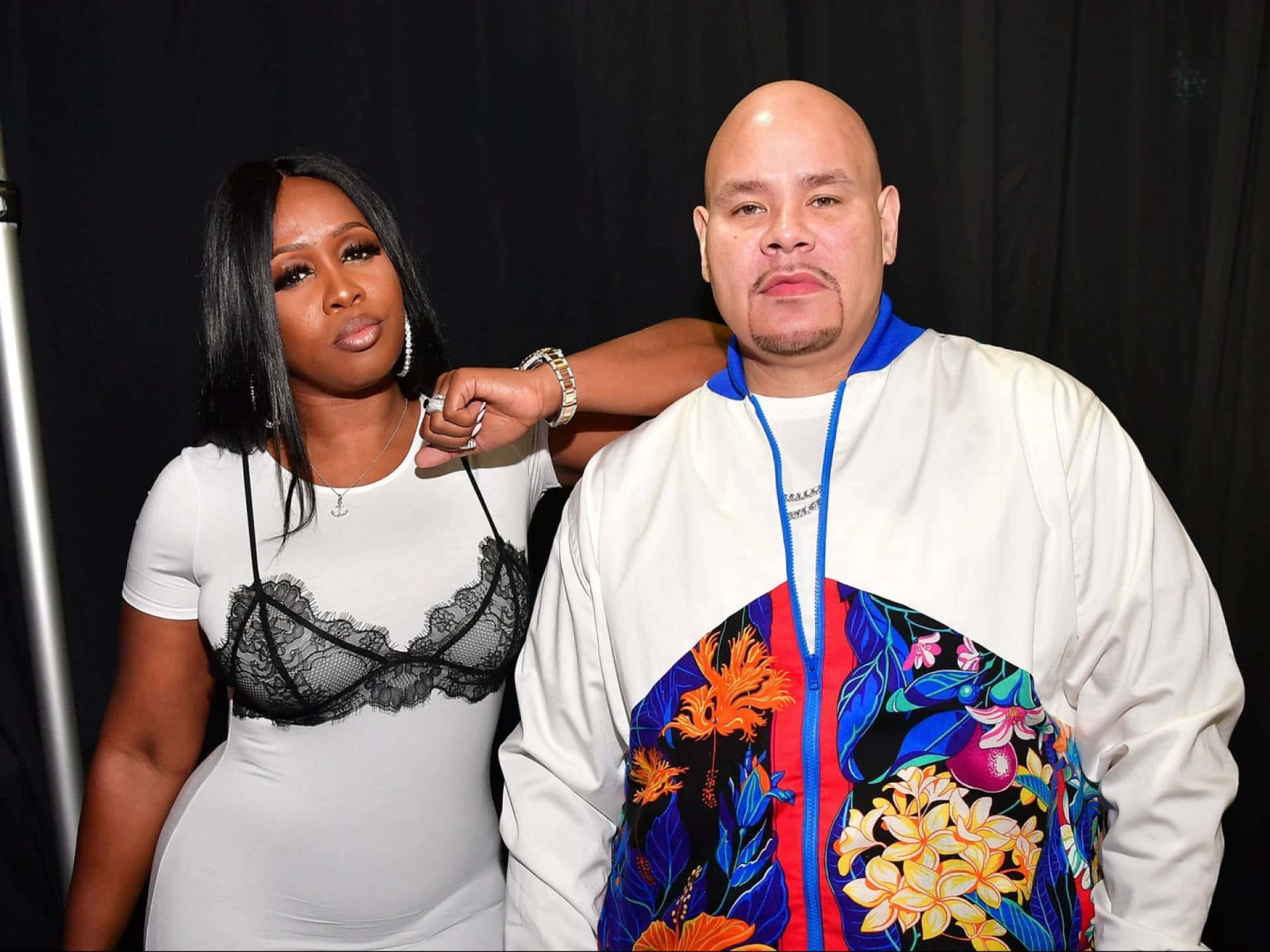  壁紙 — 一位身穿白色蕾絲上衣的女性站在一位身穿彩色花卉外套的男性旁邊，背景為黑色。