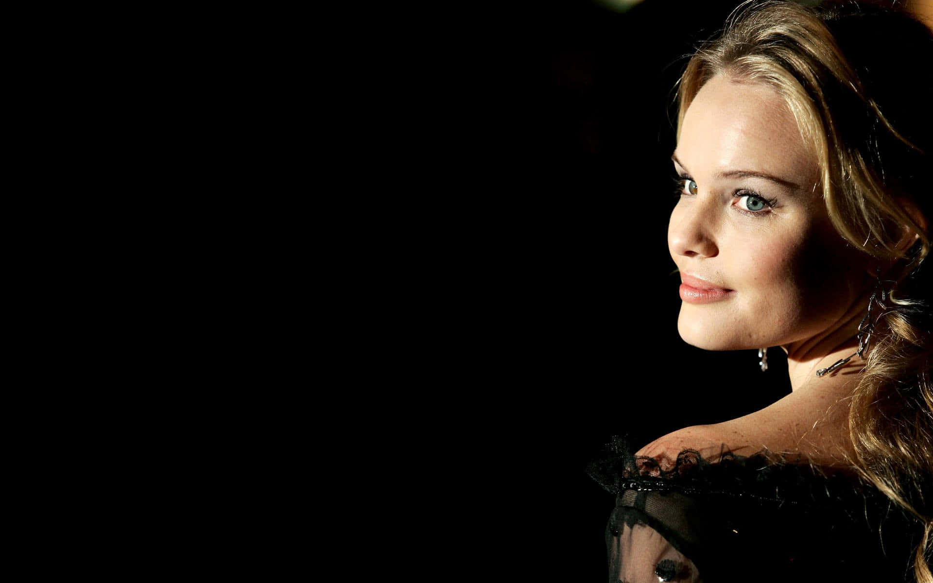 Kate Bosworth 桌布 壁紙 — 一位金髮藍眼的女性在純黑背景下，柔和燈光照射下，若有所思地凝視著。