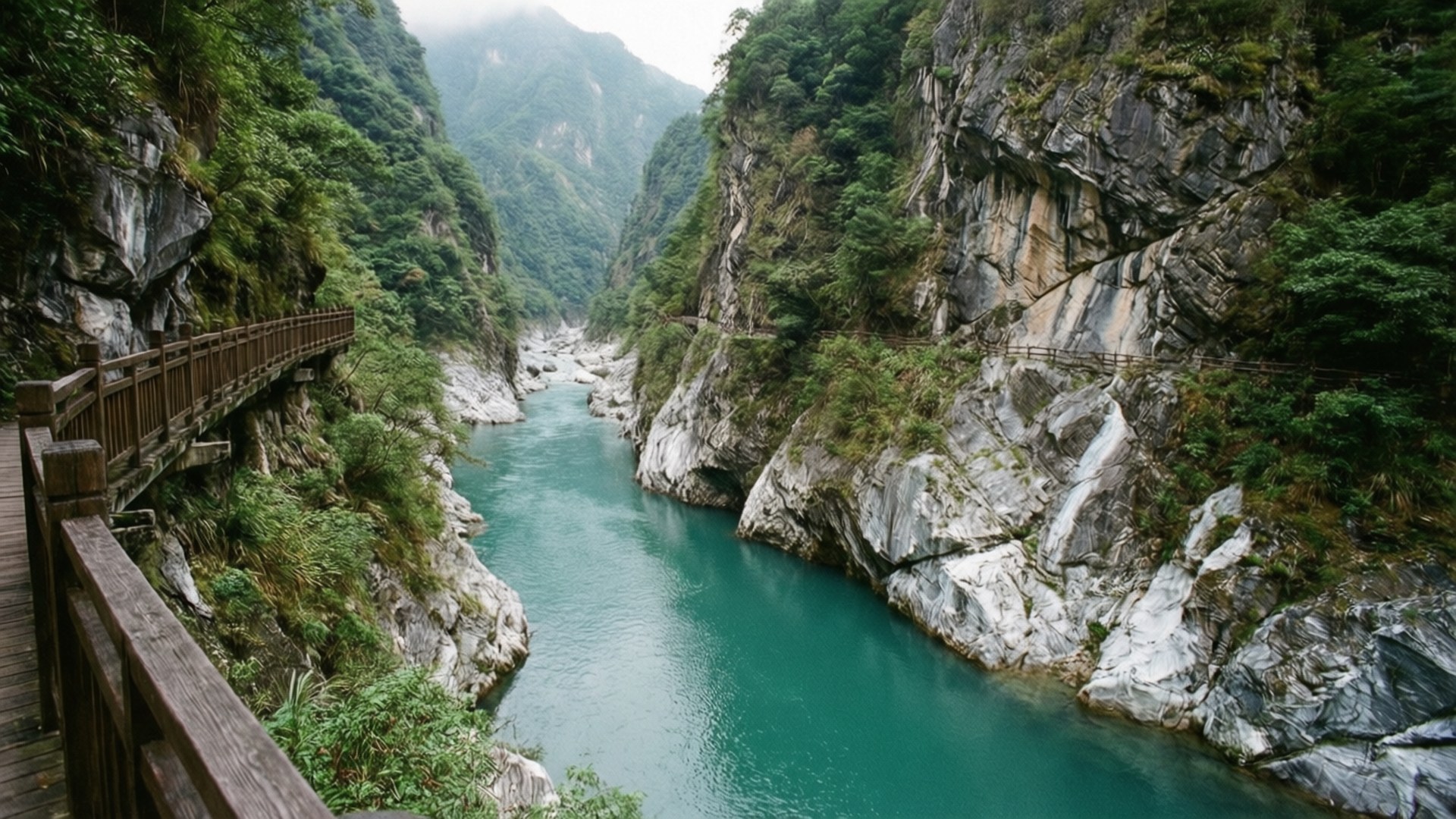 一條木徑沿著碧綠色的河流穿過陡峭的岩石峽谷，兩旁綠樹成蔭。 — 台灣 壁紙