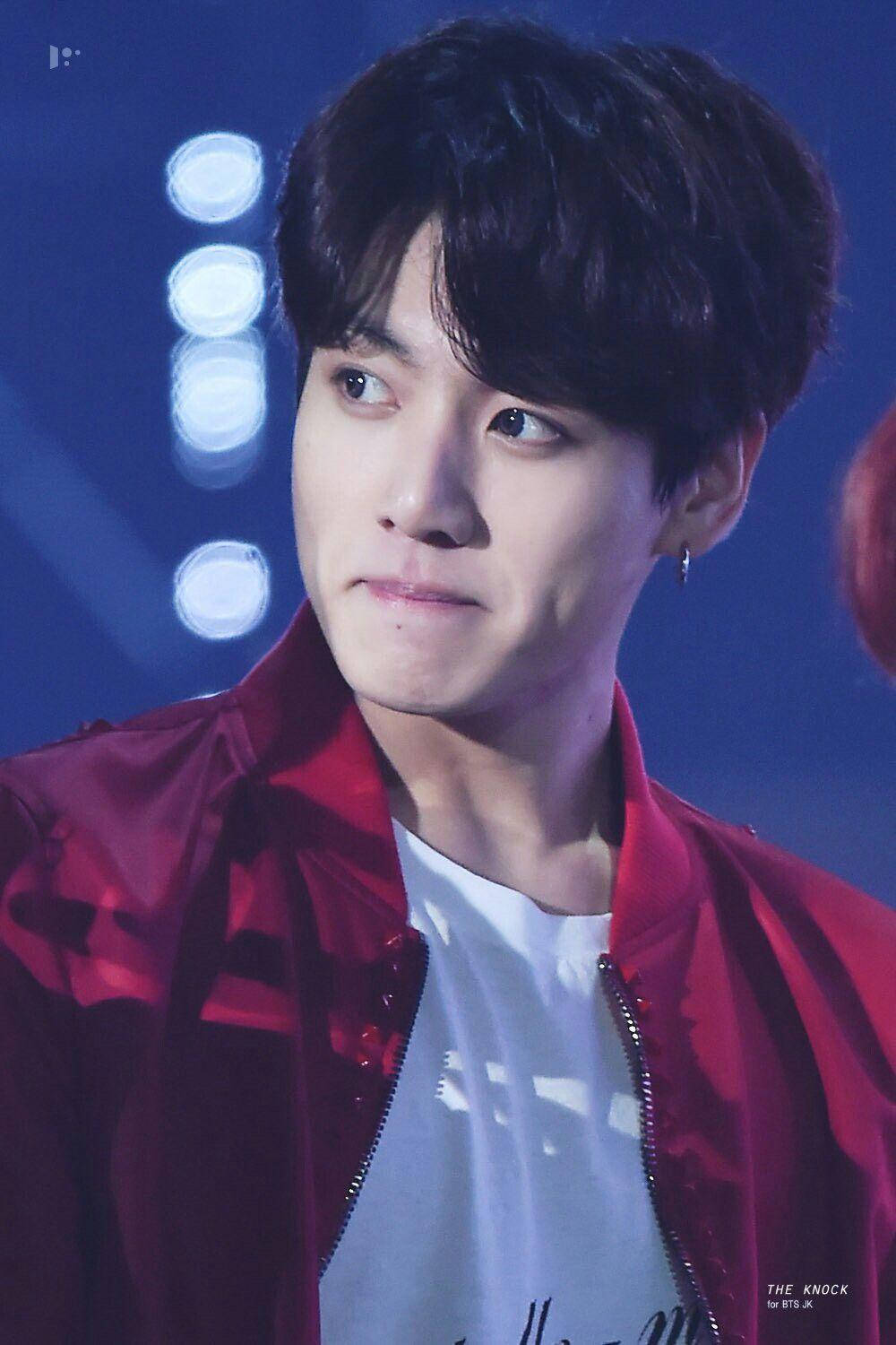 韓國男表演者在舞台燈光下穿著紅色外套，表情嚴肅。 — Bts 壁紙
