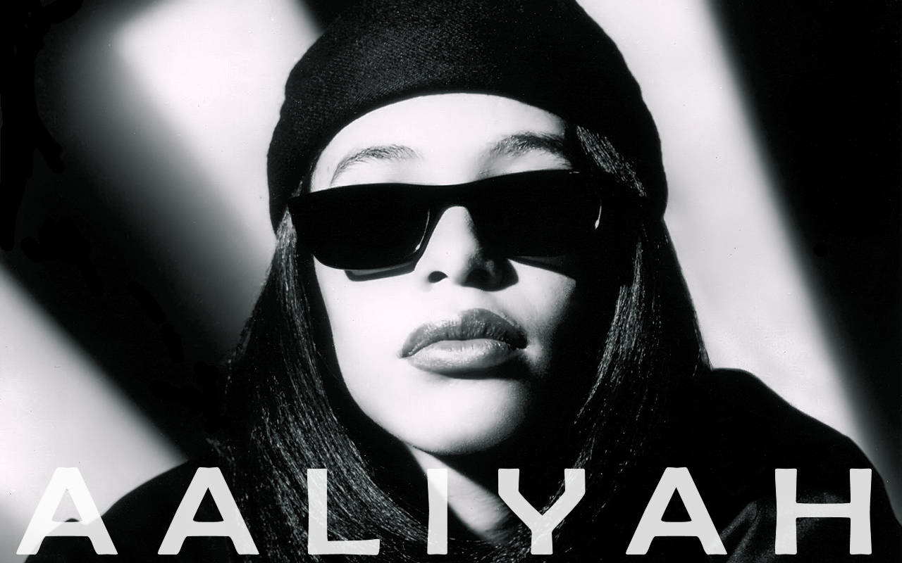 aaliyah 桌布 壁紙 — Aaliyah 戴著太陽眼鏡和毛帽的黑白肖像照，燈光效果強烈。