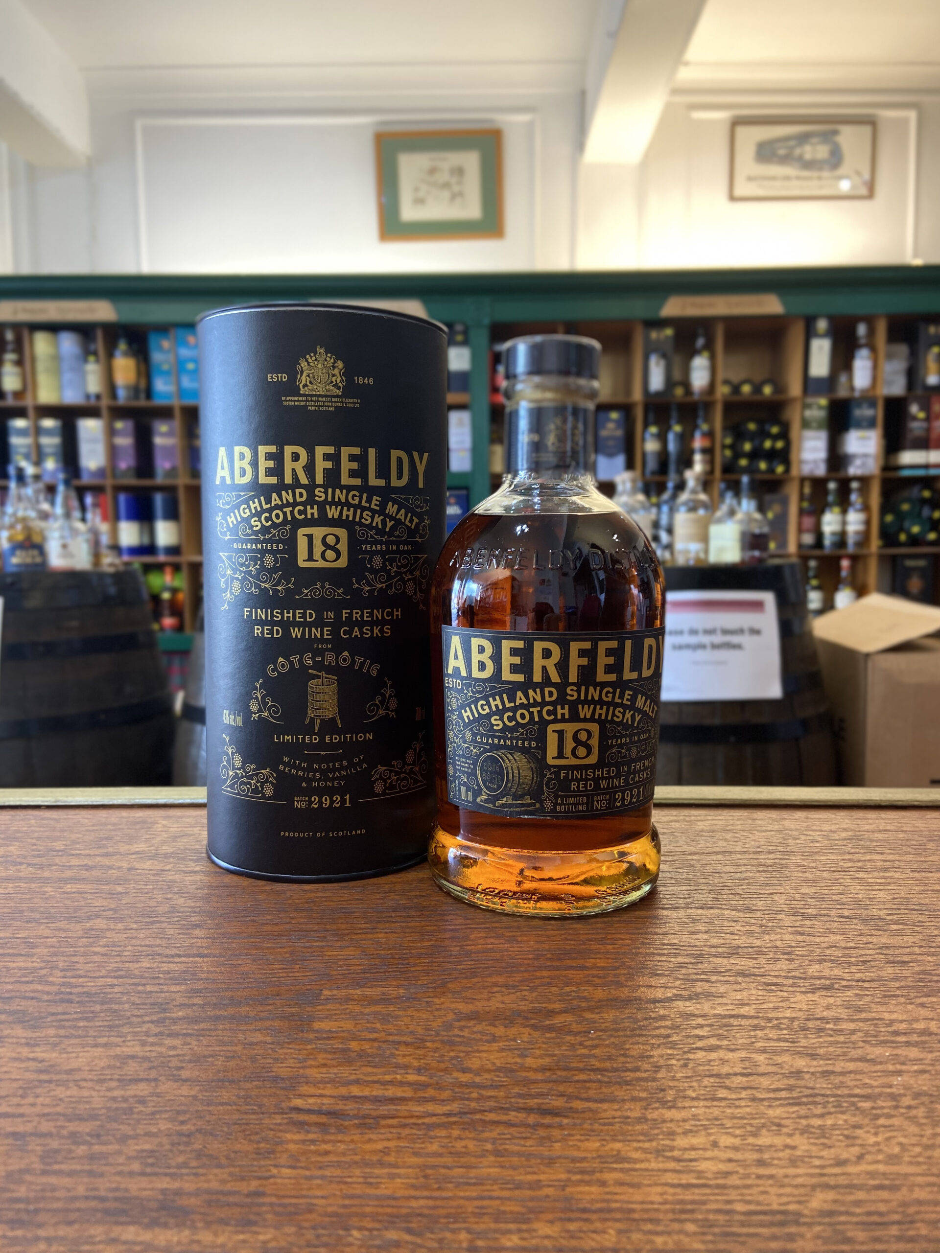 Drink 桌布 壁紙 — Aberfeldy 18年高地單一麥芽蘇格蘭威士忌酒瓶和禮盒放在一家貨品齊全的威士忌店的木質櫃檯上。