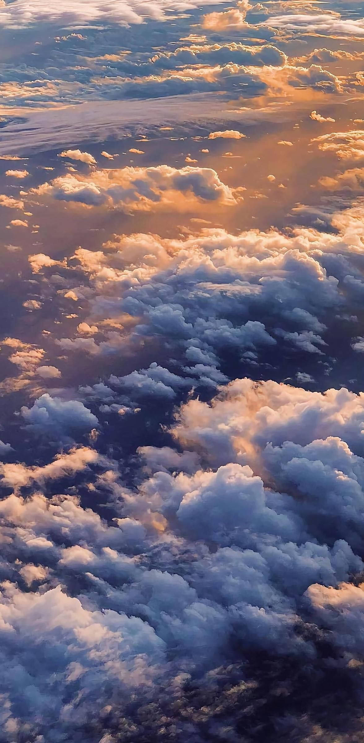 Above The Clouds iPhone 12 壁紙 — 從高空俯瞰蓬鬆的雲朵沐浴在金色夕陽光中，下方是深藍色的陰影。