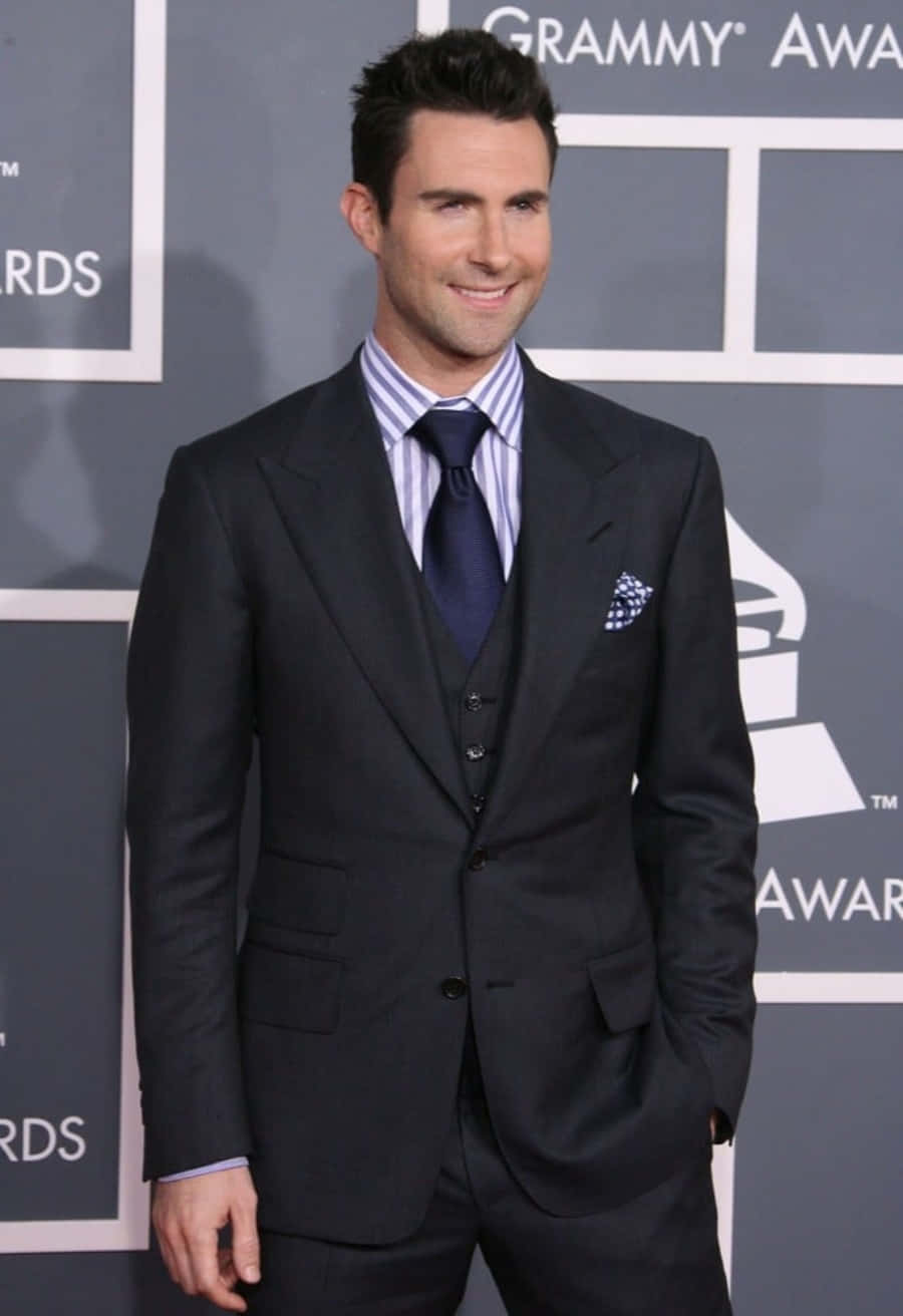 Adam Levine 桌布 壁紙 — Adam Levine 在葛萊美獎紅地毯上穿著俐落的黑色西裝，自信地微笑。