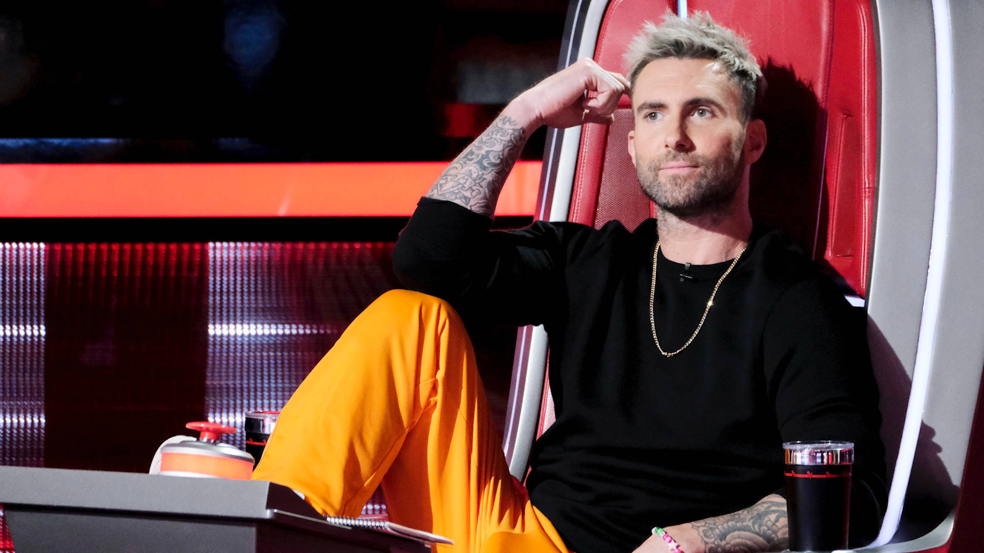 Adam Levine 桌布 壁紙 — Adam Levine 自信地靠在他《The Voice》標誌性的紅色評審椅上，刺青清晰可見，金鍊閃閃發光。