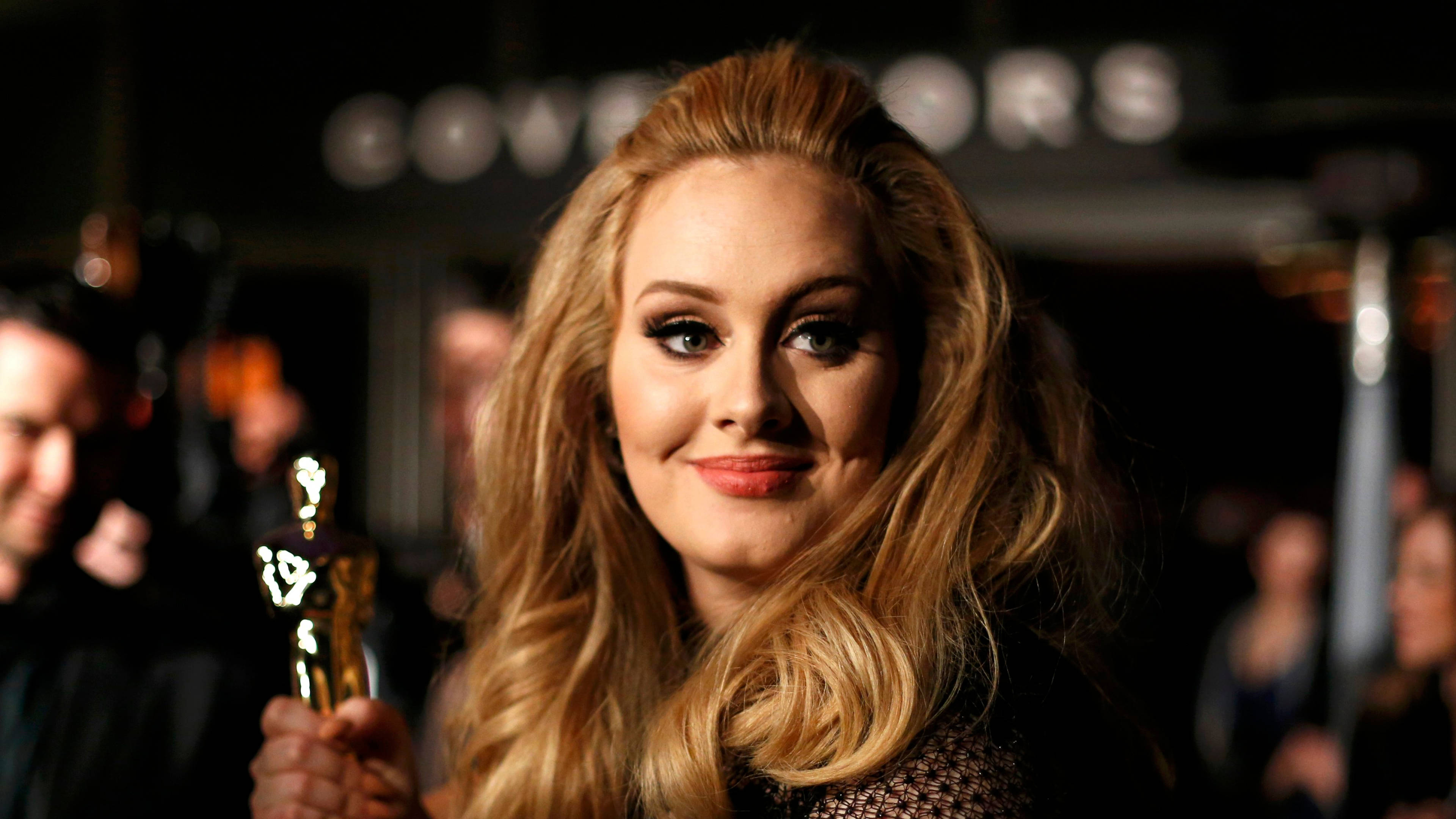 Adele 桌布 壁紙 — Adele 在柔和的聚光燈下，於一場華麗的頒獎典禮上溫暖地微笑，手持奧斯卡獎座。