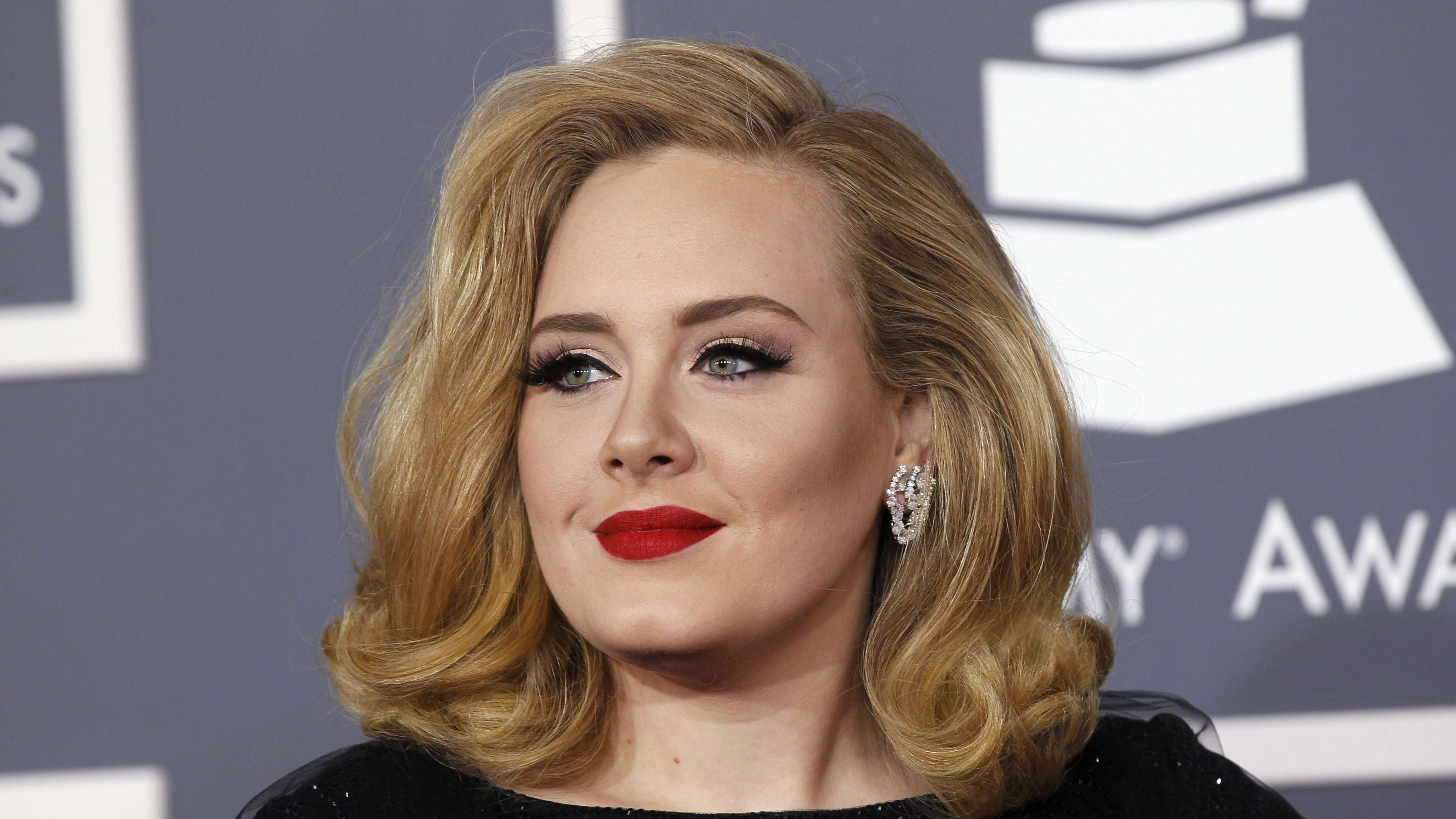 Adele 桌布 壁紙 — Adele 在葛萊美獎背景下，以大膽的紅唇和迷人的捲髮擺姿勢。