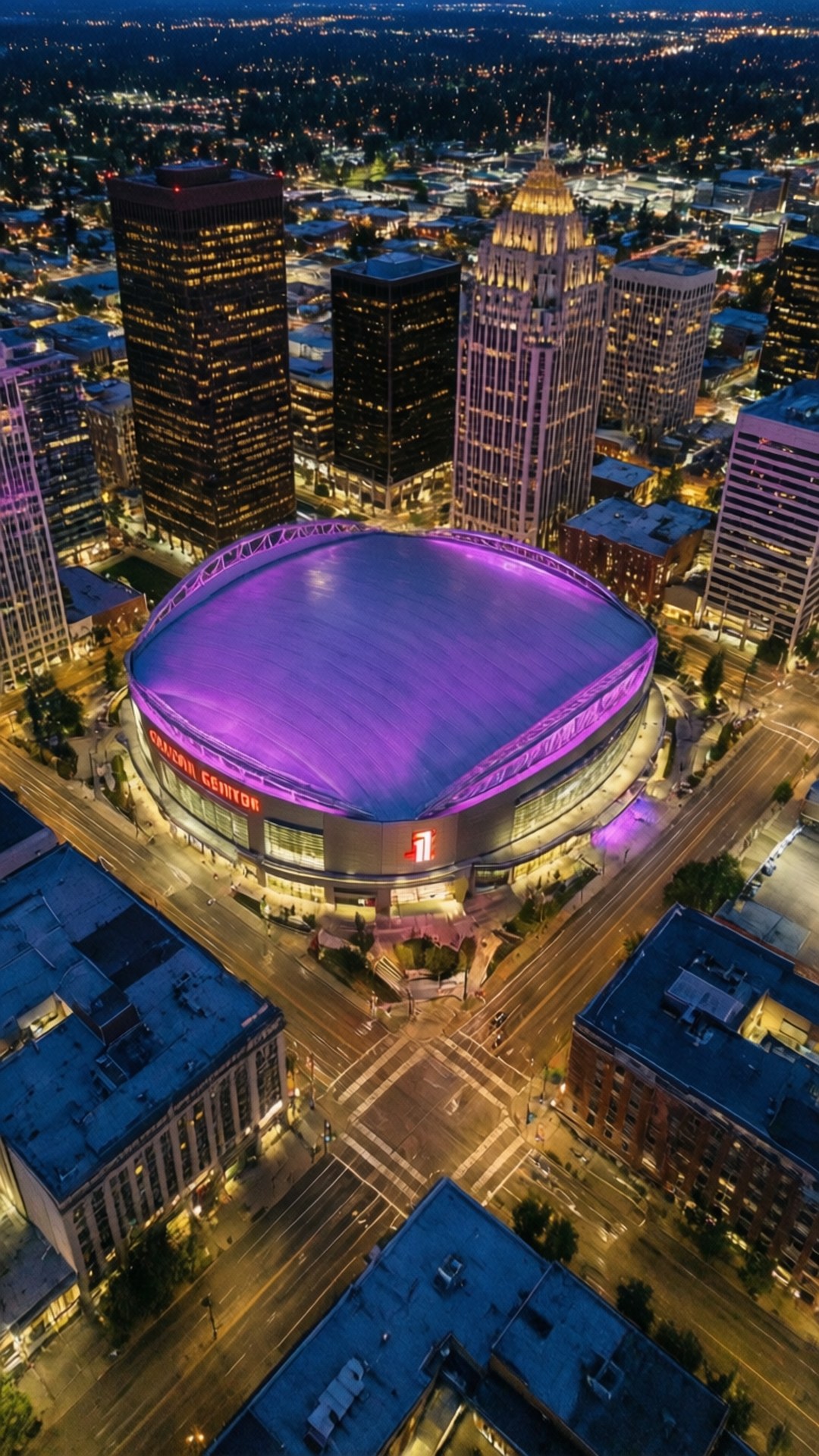 Aerial Downtown Kings 壁紙 — 夜晚鳥瞰一個發光的紫色圓頂競技場，周圍環繞著燈火通明的摩天大樓和城市街道。
