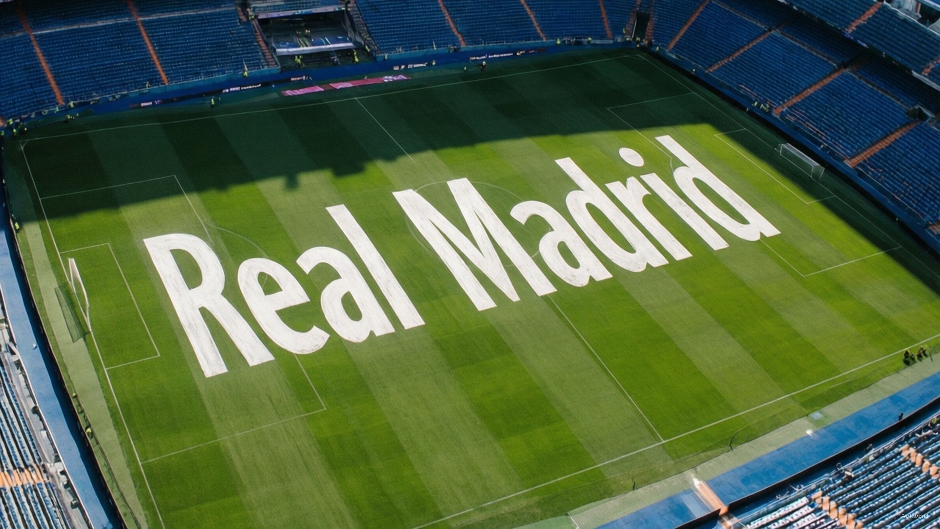 Bernabéu Pitch Art 壁紙 — 足球場的鳥瞰圖，在充滿活力的綠色球場上，有大型白色字母 'Real Madrid'，周圍環繞著藍色座位。
