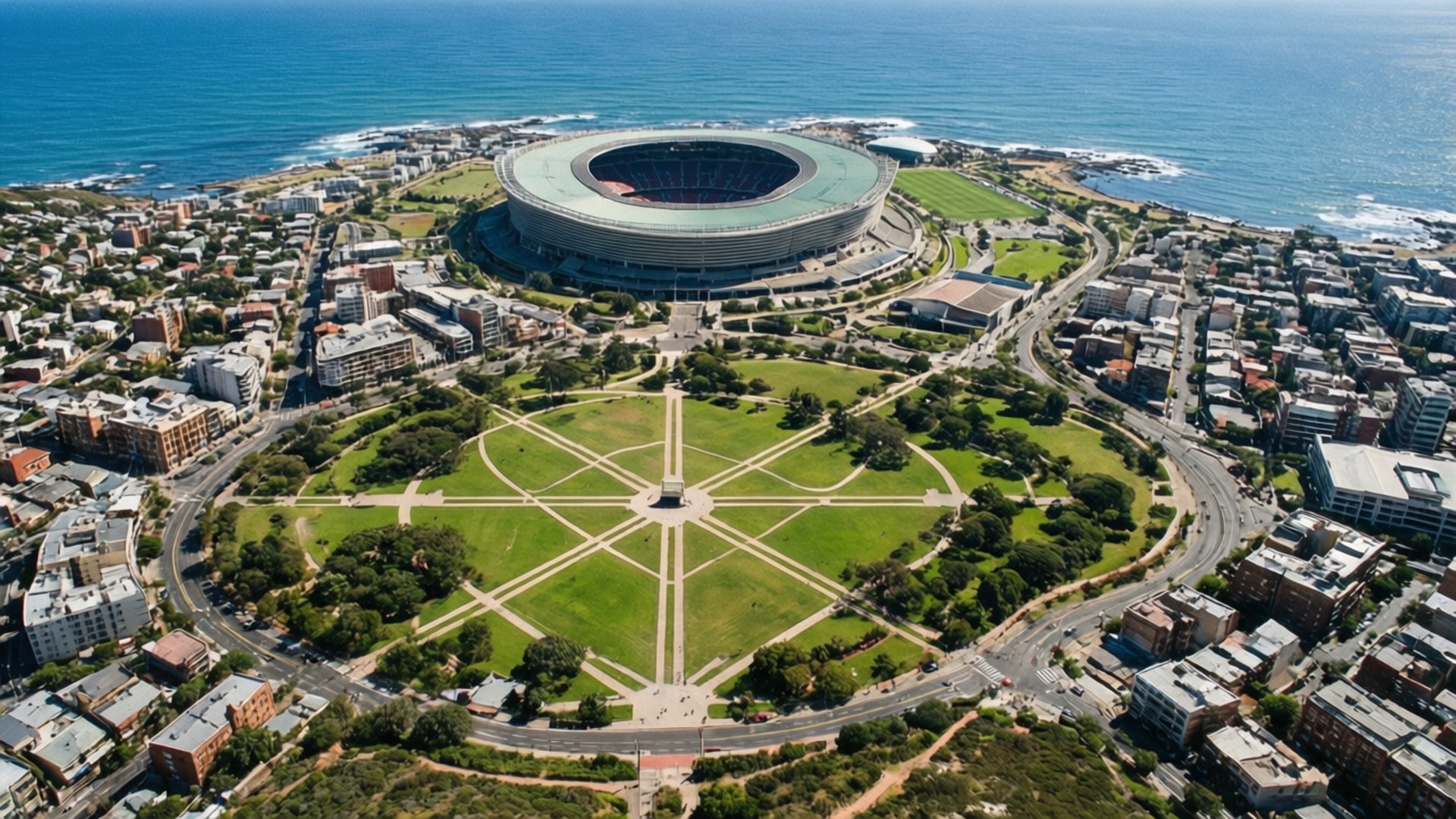 Stadium and Common 壁紙 — 俯瞰現代圓形體育館坐落於海邊，前景是幾何圖案的綠色公園。