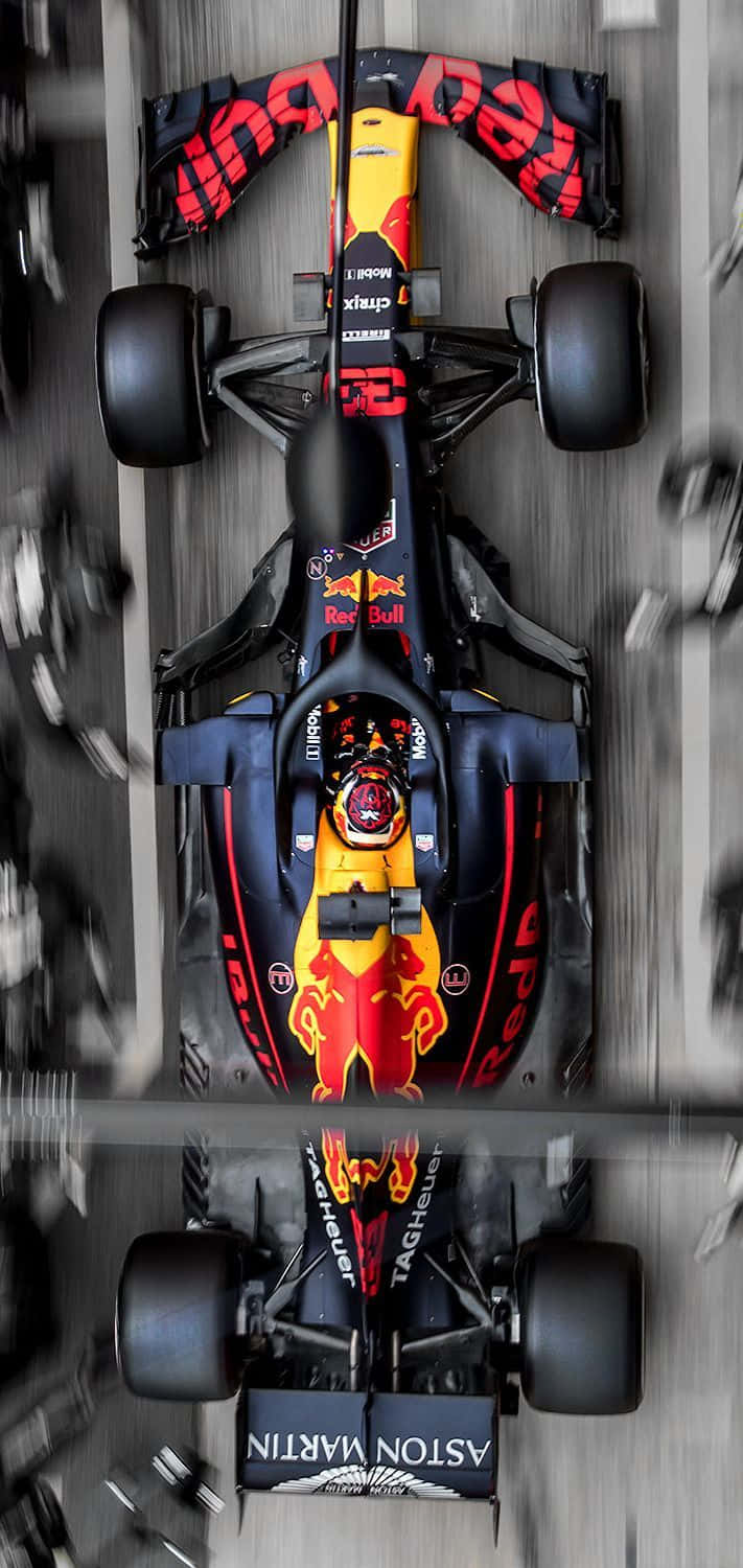 Max Verstappen 桌布 壁紙 — Red Bull Racing 一級方程式賽車在賽道上高速行駛的空中視角，帶有動態模糊和反光表面。