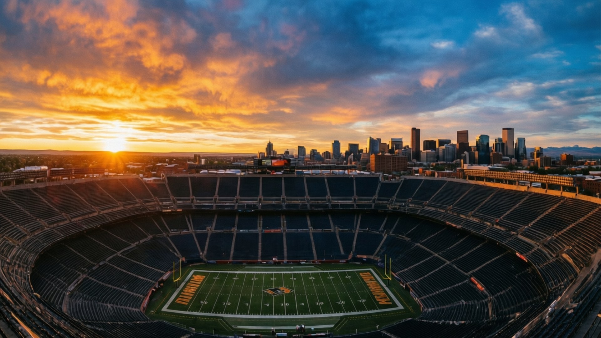 Mile High Stadium Sunset 壁紙 — 空無一人的足球場在日落時的鳥瞰圖，城市天際線上方有充滿活力的橙色和藍色天空。