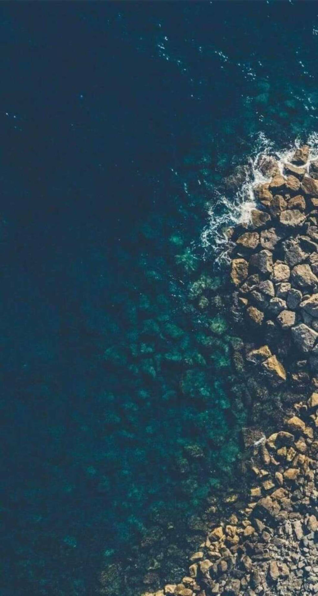 海浪拍打岩石海岸線，海水清澈碧綠。 — 主畫面 壁紙