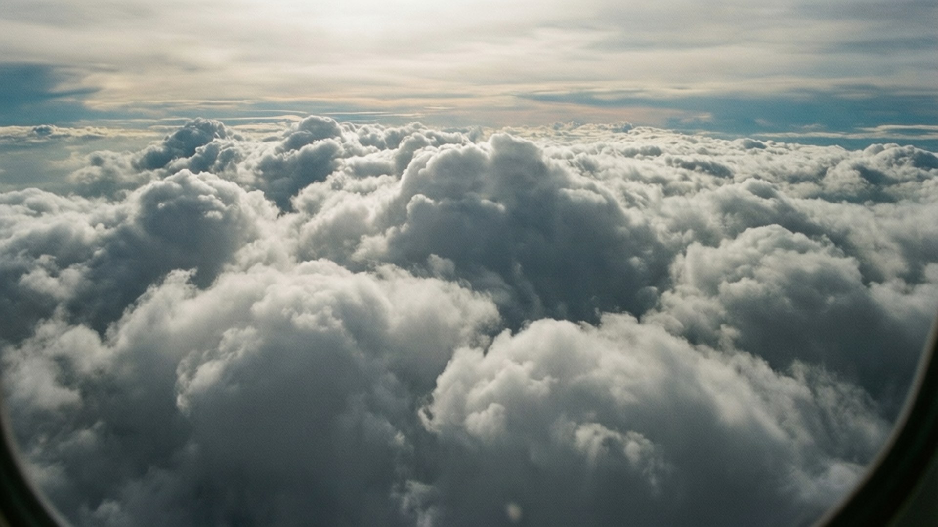 Above the Cloud Blanket 壁紙 — 從飛機窗戶看到的航空視圖，柔軟的金色天空下綿延不絕的蓬鬆白雲。