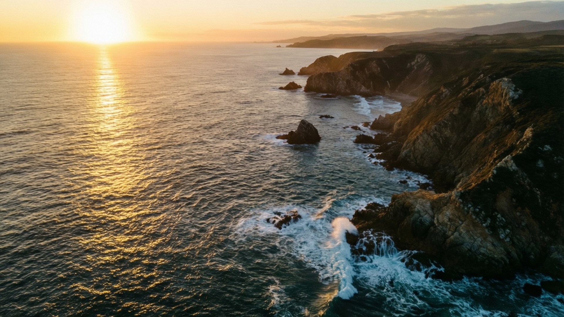 Coastal Aerial Sunset 壁紙 — 崎嶇海岸懸崖上金色日落、拍岸浪花與閃爍大海的鳥瞰圖。