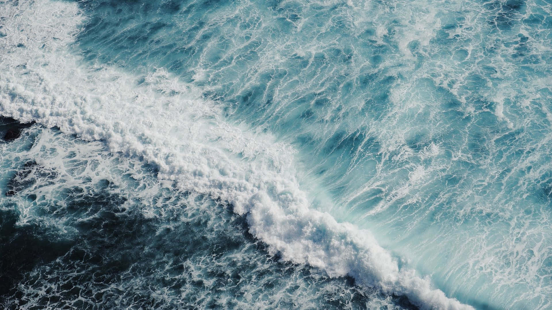  壁紙 — 從高空俯瞰洶湧的海浪拍打著深藍色海水，激起白色泡沫。