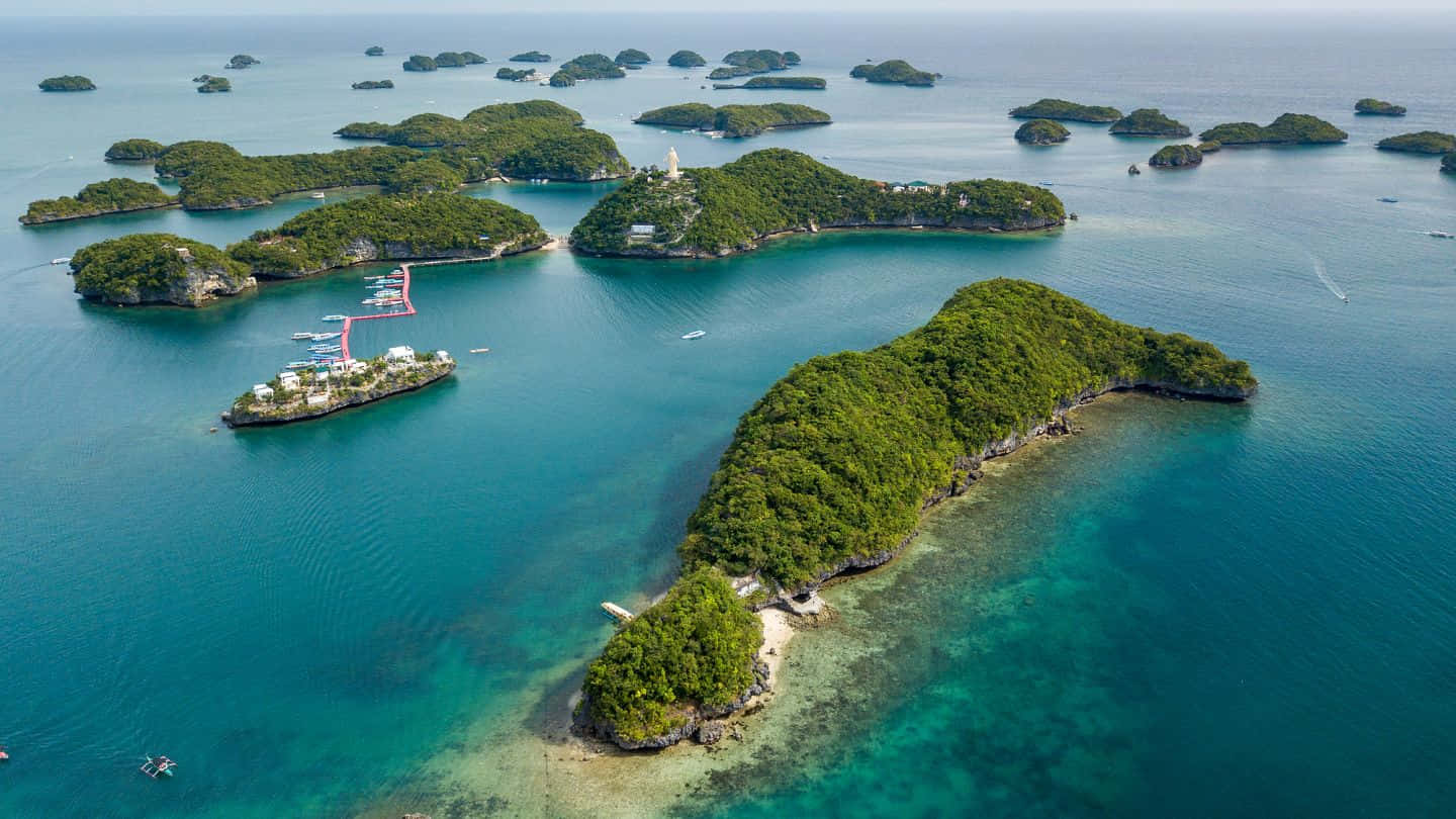  壁紙 — 鳥瞰圖：碧綠海水點綴著翠綠島嶼，島上有度假村和船隻。