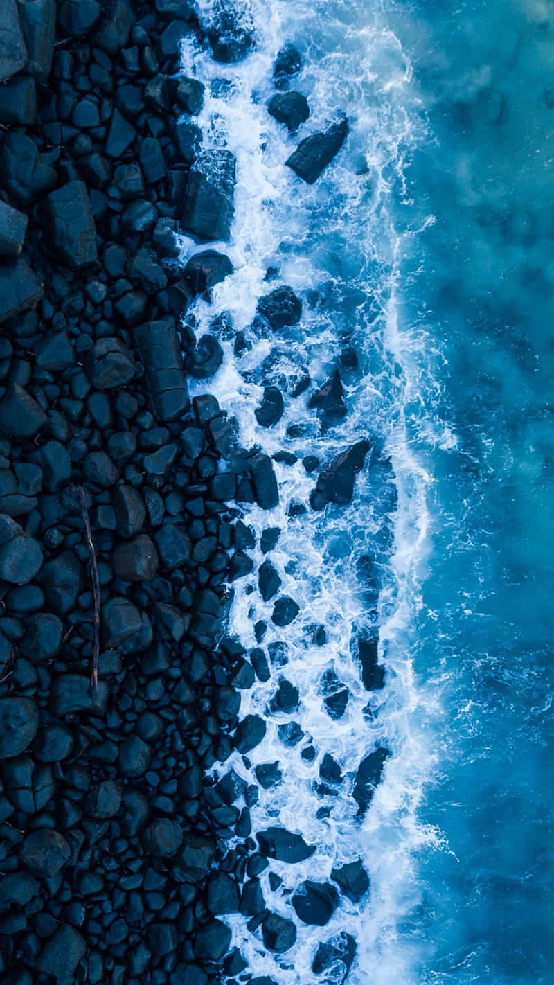  壁紙 — 從高空俯瞰，碧綠色的海浪拍打著崎嶇的黑色岩石海岸線。