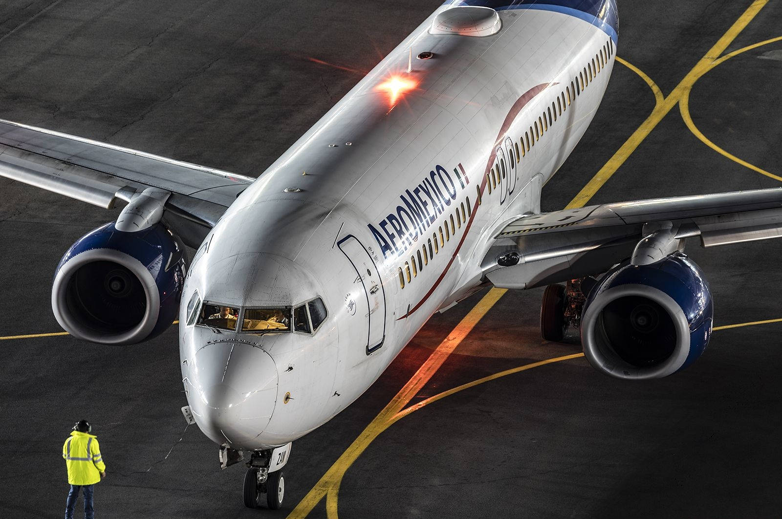 Airport 桌布 壁紙 — Aeromexico 飛機在停機坪上的夜間高角度拍攝，附近有身穿黃色背心的地勤人員。