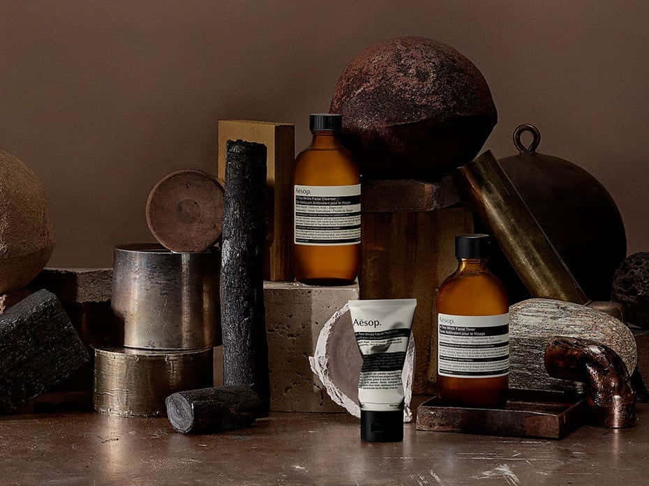 shoot 桌布 壁紙 — Aesop護膚產品展示在質樸的金屬和石頭物品之間，呈現溫暖的大地色調。