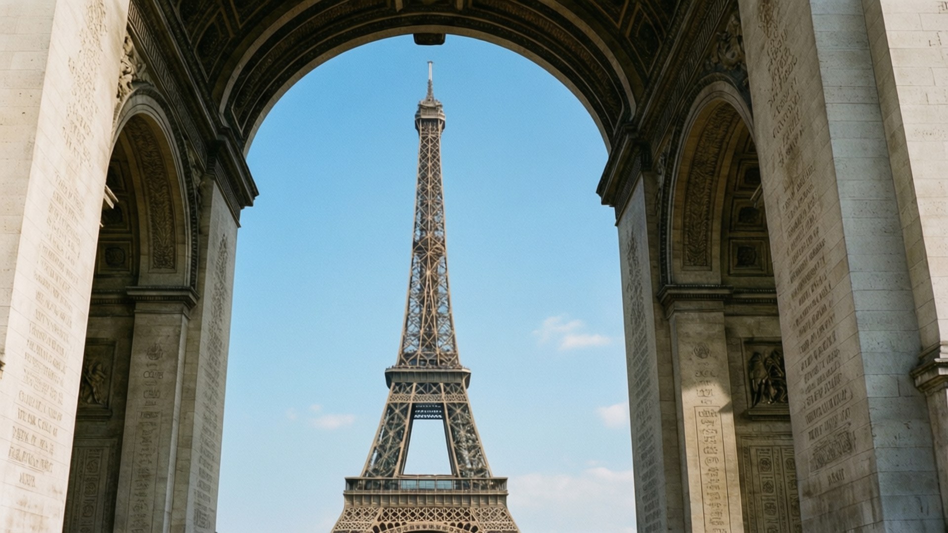Through the Arc de Triomphe 壁紙 — 艾菲爾鐵塔在巴黎凱旋門的巨大拱門框著的清澈藍天下高高聳立。
