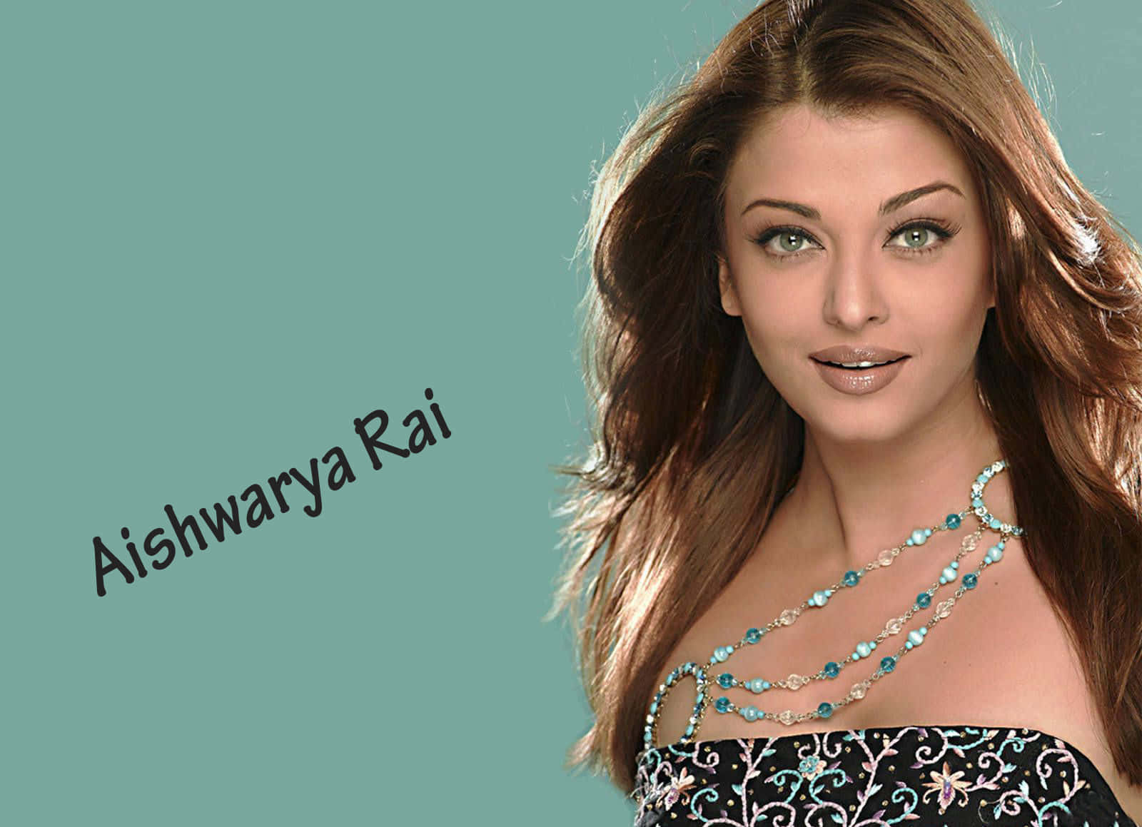 Aishwarya Rai 桌布 壁紙 — Aishwarya Rai 擁有飄逸的棕色頭髮和綠松石首飾，背景為純青色。