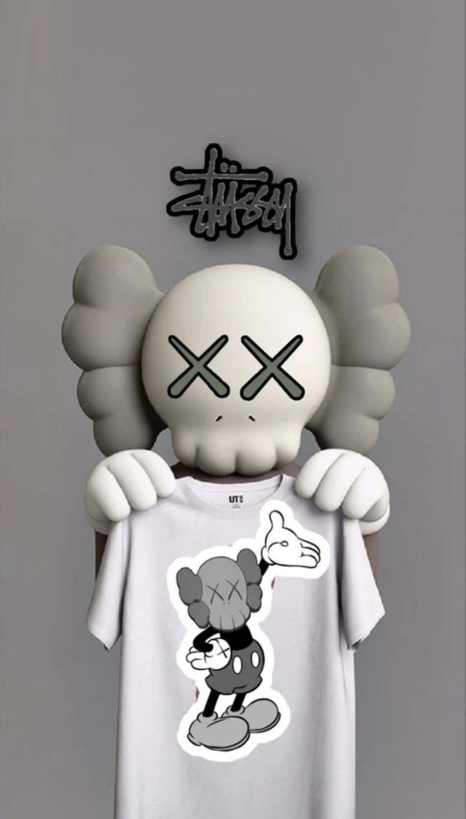 kaws pc 桌布 壁紙 — AKA KAWS 雕塑手持一件白色T恤，上面貼有灰色米奇老鼠貼紙，背景是純灰色牆壁。
