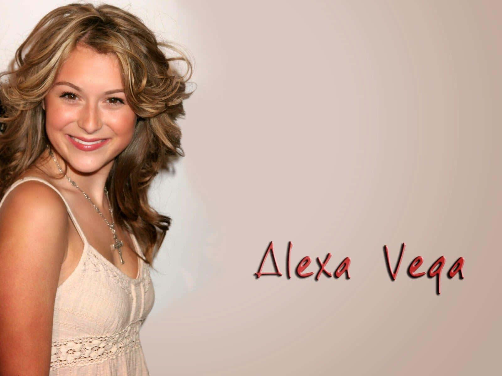 Alexa Penavega 桌布 壁紙 — Alexa Vega 在柔和米色背景前，穿著奶油色蕾絲上衣，溫暖微笑，她的名字用紅色寫出。