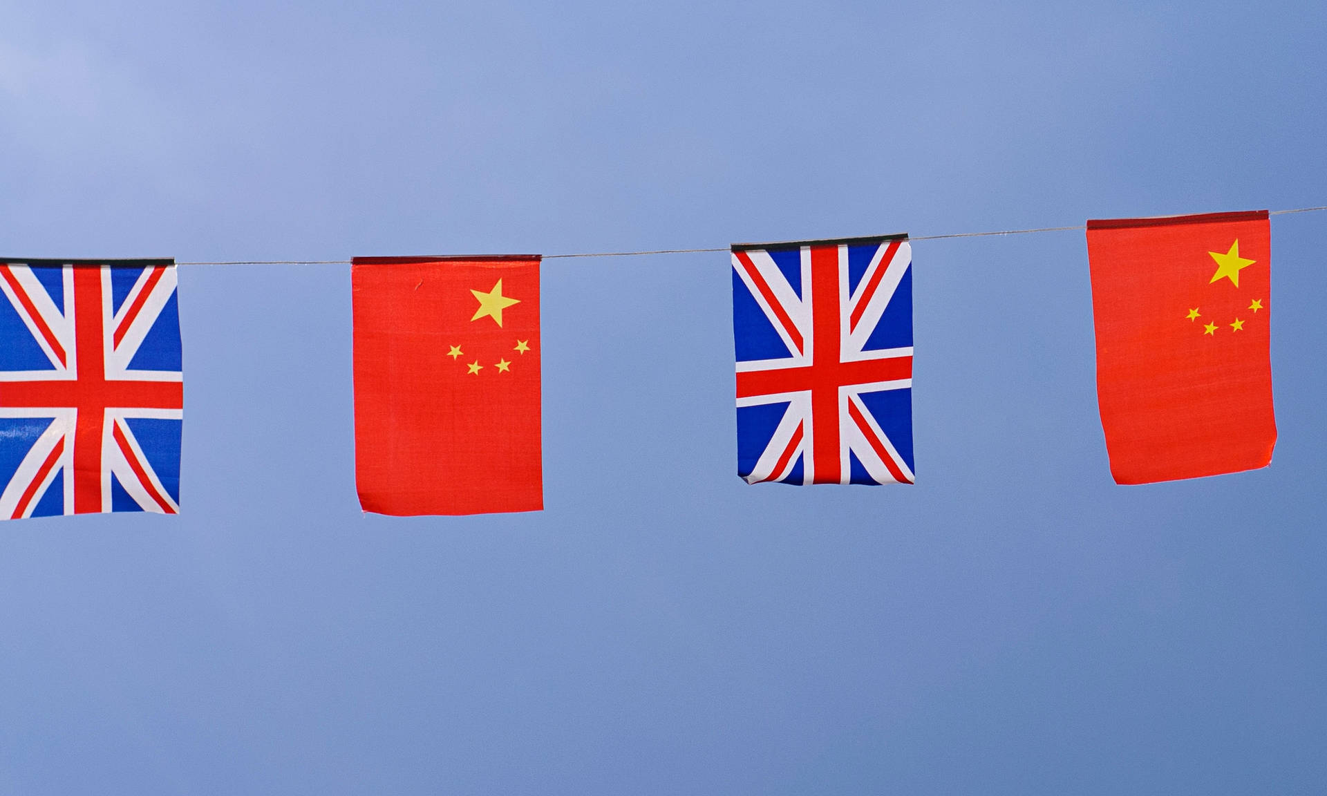 中國和英國國旗交替掛在一條線上，襯著藍天。 — 中國國旗 壁紙