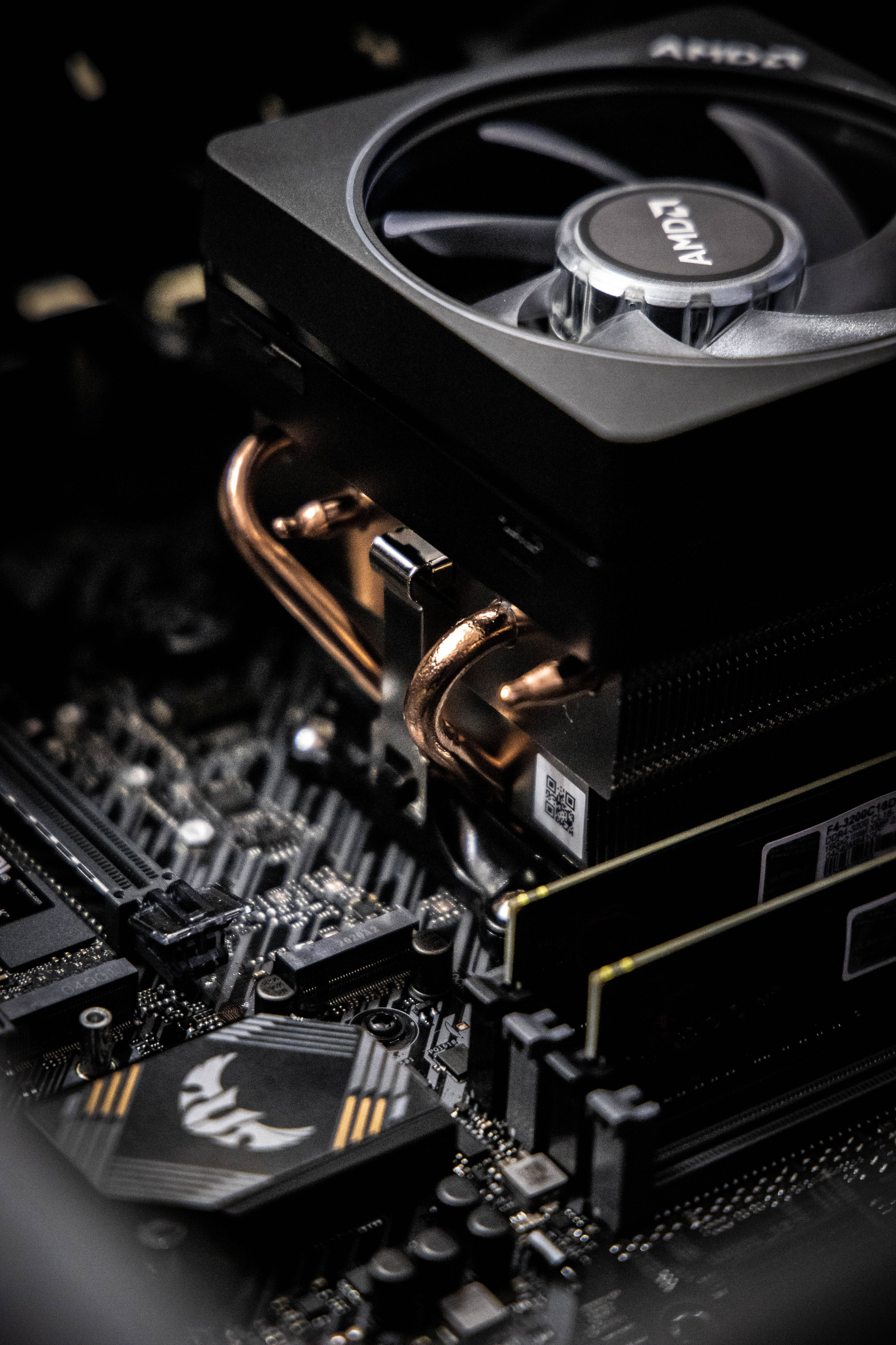 科技動圖 桌布 壁紙 — AMD CPU 散熱器特寫，帶有銅管，安裝在帶有發光標誌的黑色主機板上。