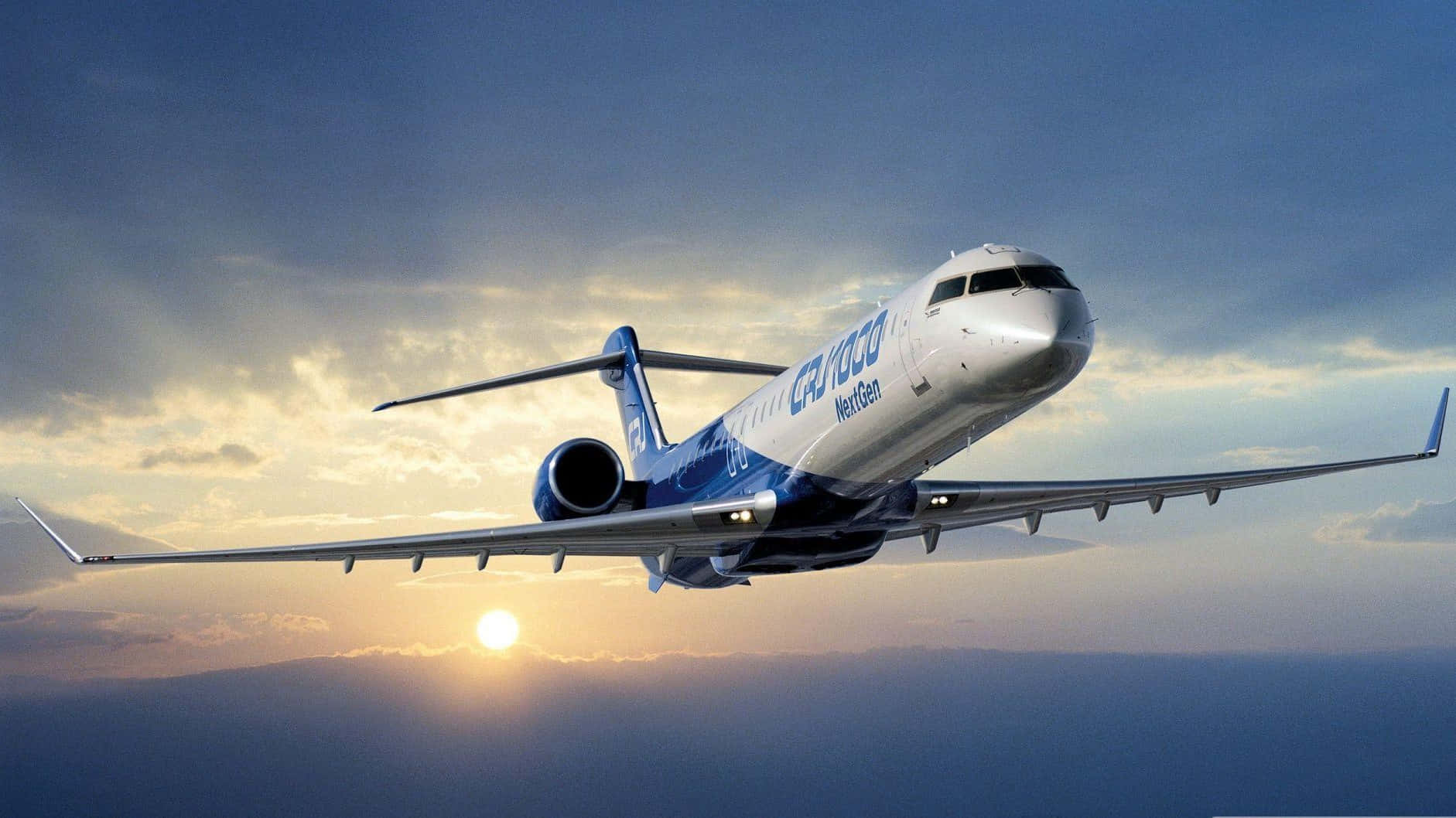 Plane 桌布 壁紙 — AmeriJet 客機在日落天空中翱翔，金色的太陽低掛在地平線上，為雲層投下溫暖的光芒。
