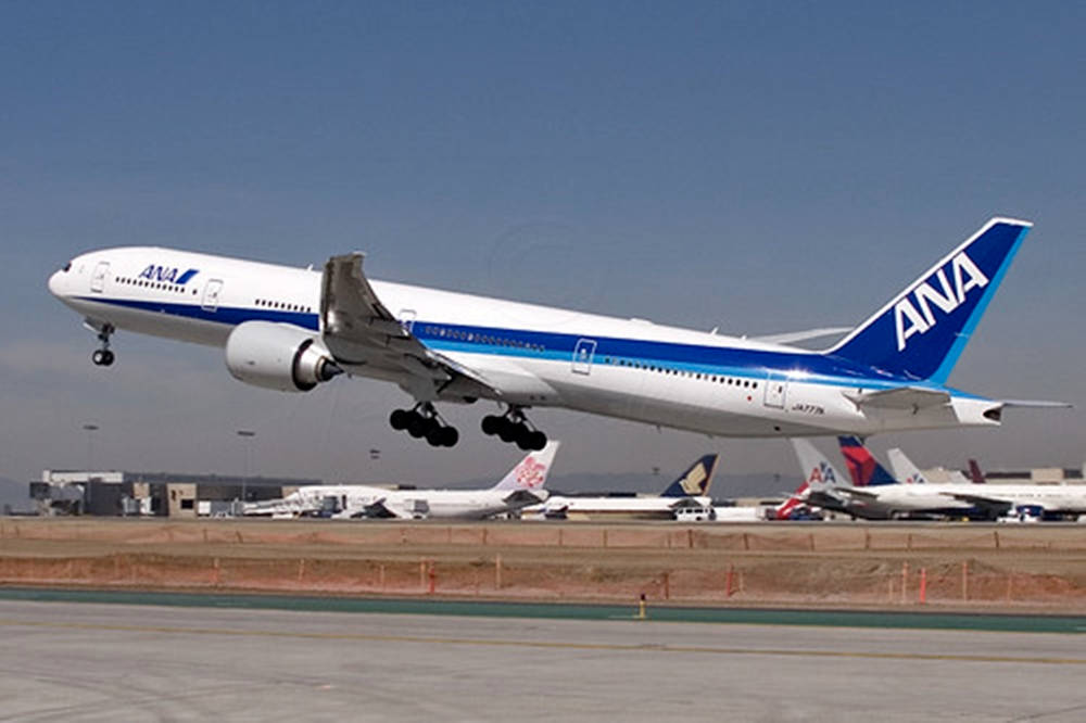  壁紙 — ANA波音777在晴朗藍天下起飛，下方停機坪有其他飛機停泊。